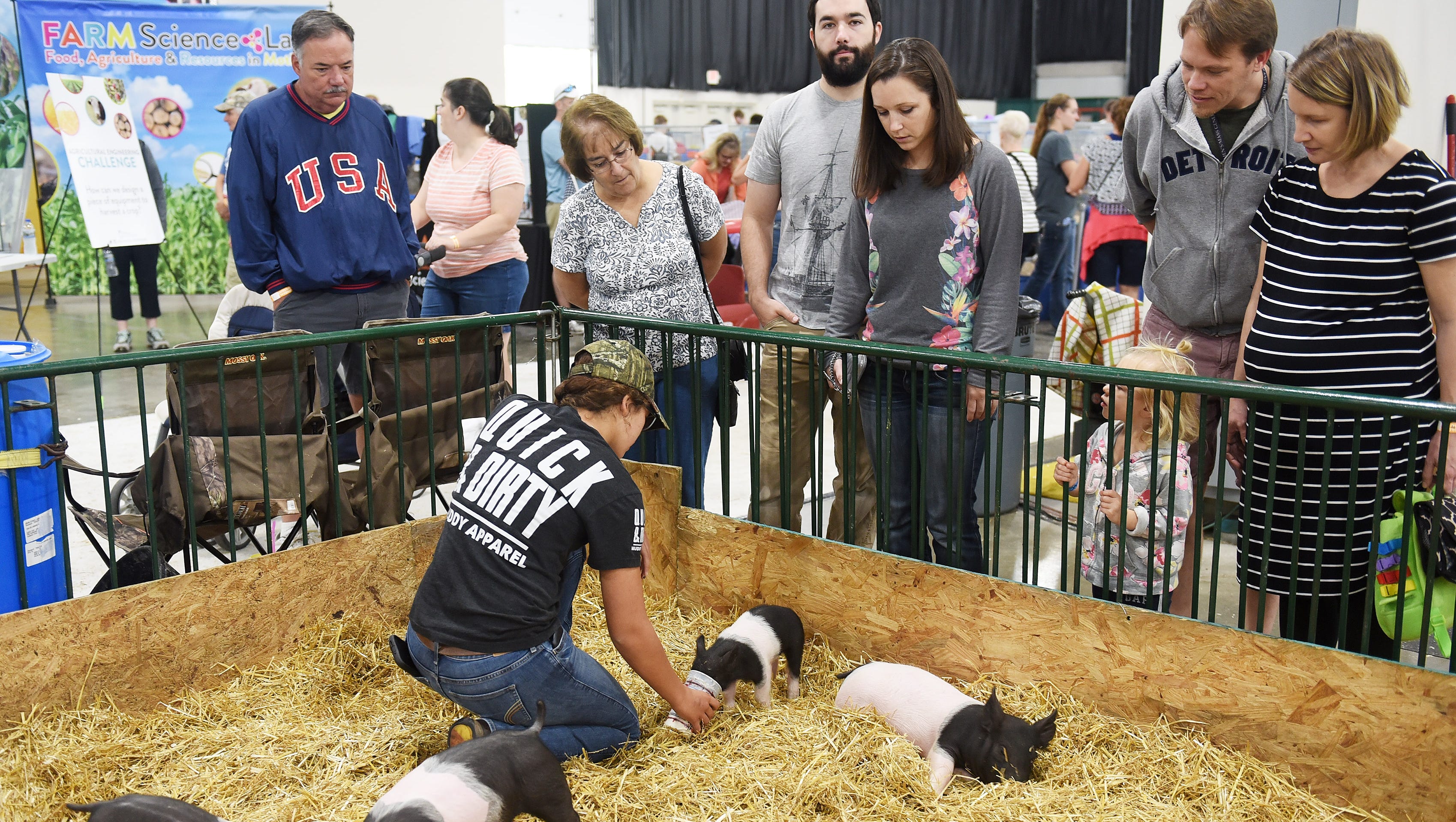 People watch as Baylee Huff, 15, of Durand feeds the runt of the litter, named Little Bit, at her display at the Michigan State Fair.