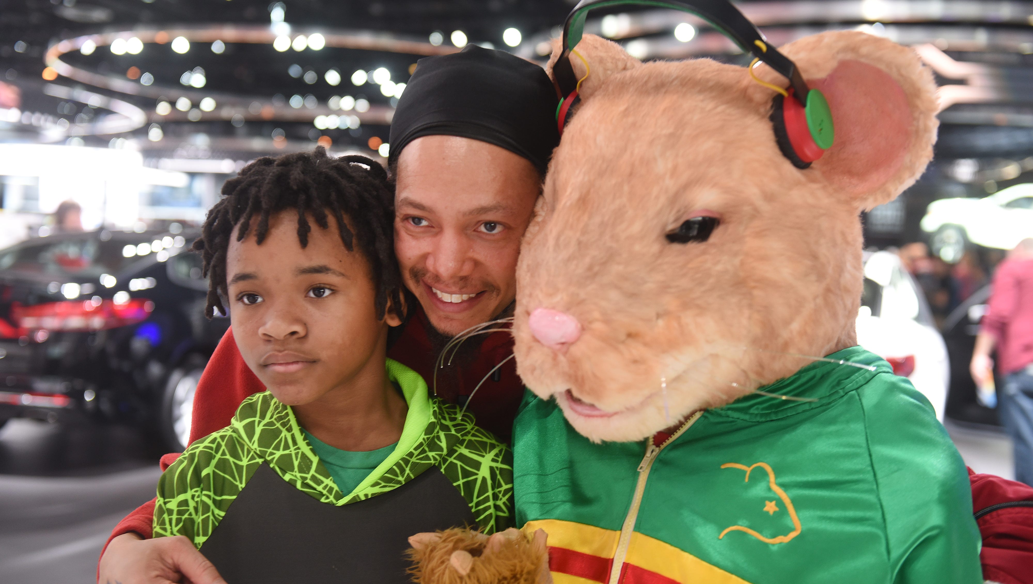 Craig Harris (center), of Cleveland, with his nephew Brandon Hayes, pose with a Kia Motors hamster at the North American International Auto Show