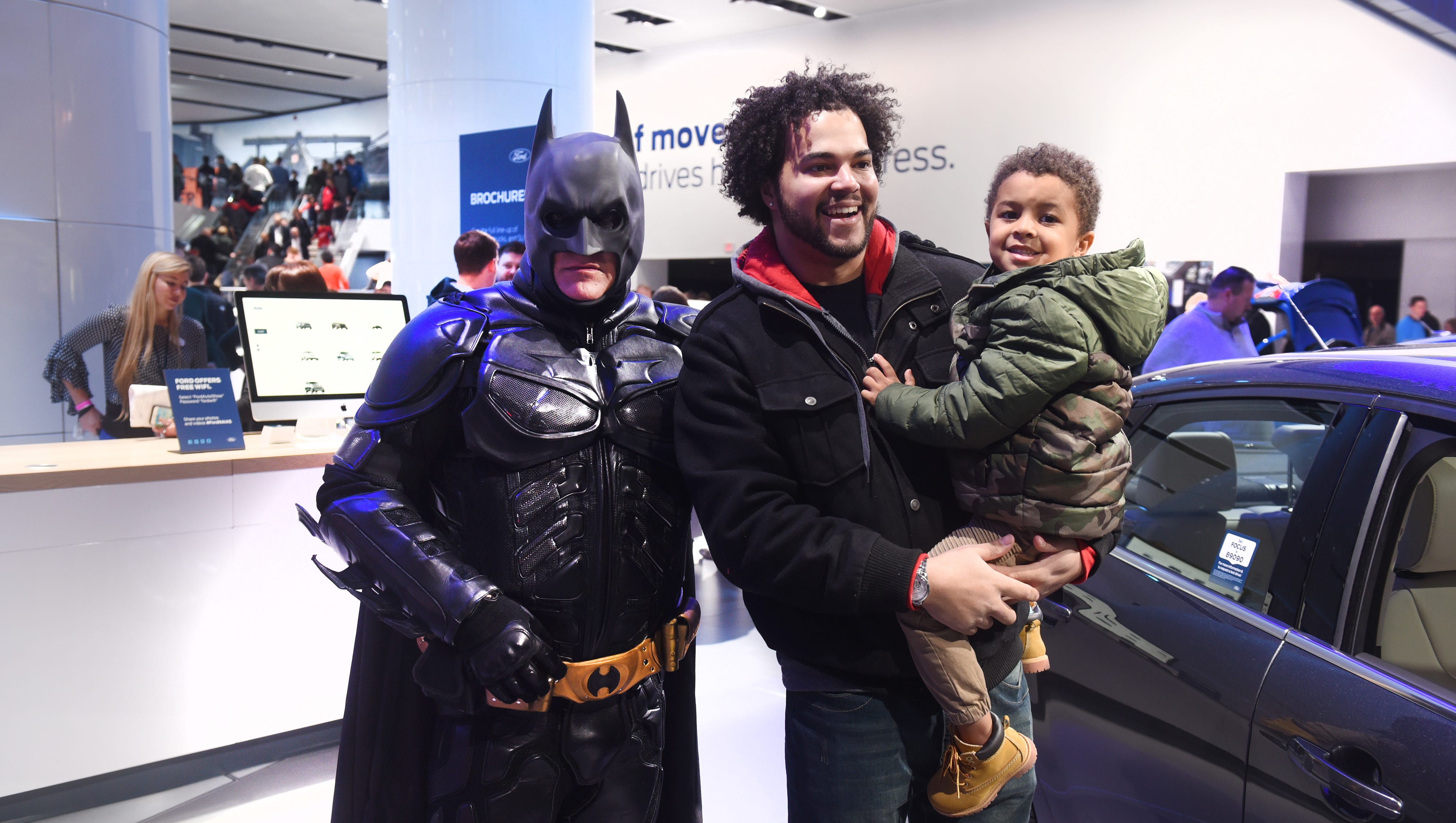 Steven Williamson (center), of Detroit, holds his son Kayden was they pose with Batman at the Ford display on Saturday January 20, 2018.