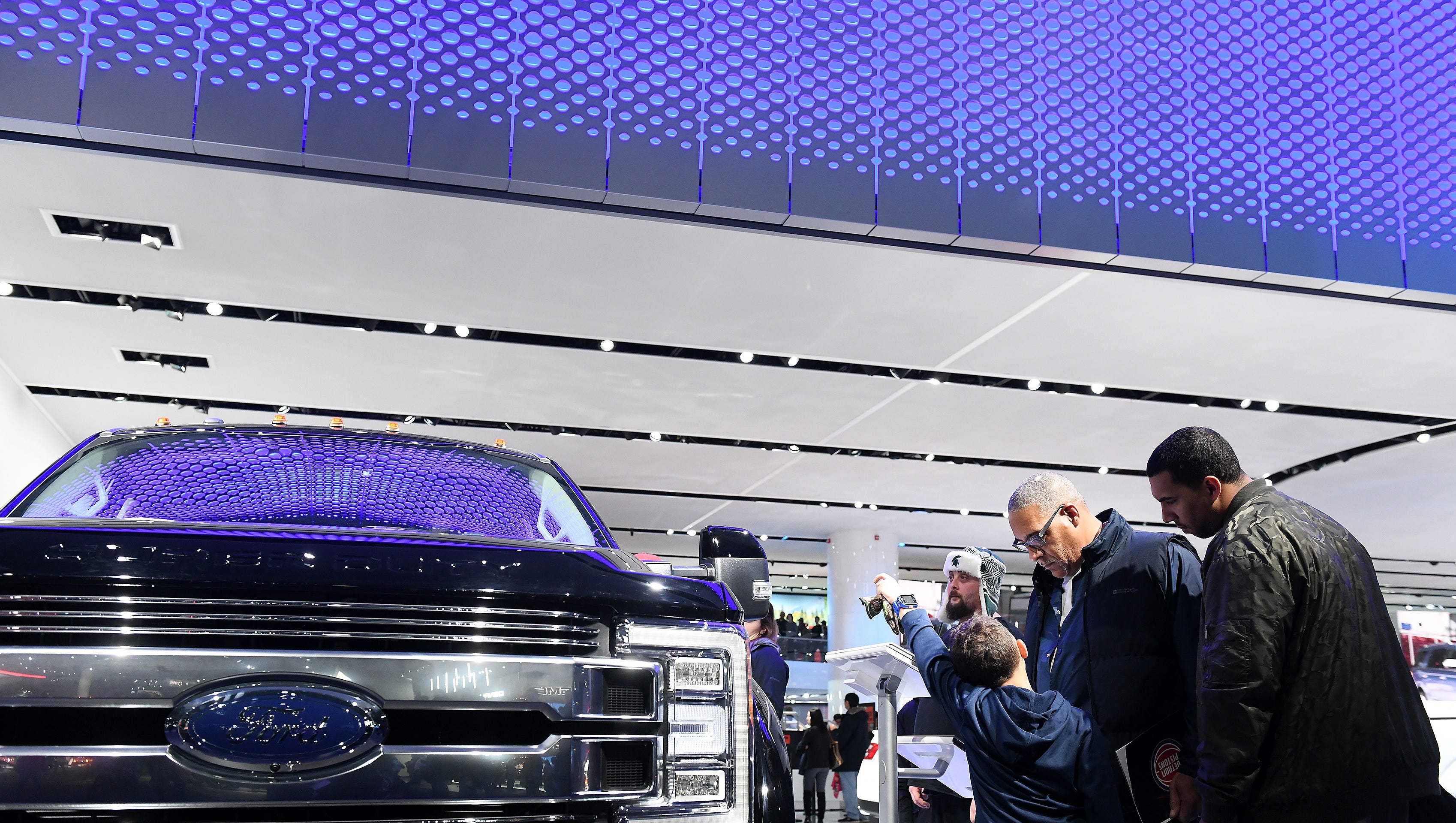 Keith Merrit of Canton, center, checks out the info on the Ford F-450 superduty truck with his sons, Travis Merritt, 8, and Kyle Merritt, 27, right, home of leave from the U.S. Air Force at the final day of the North American International Auto Show.