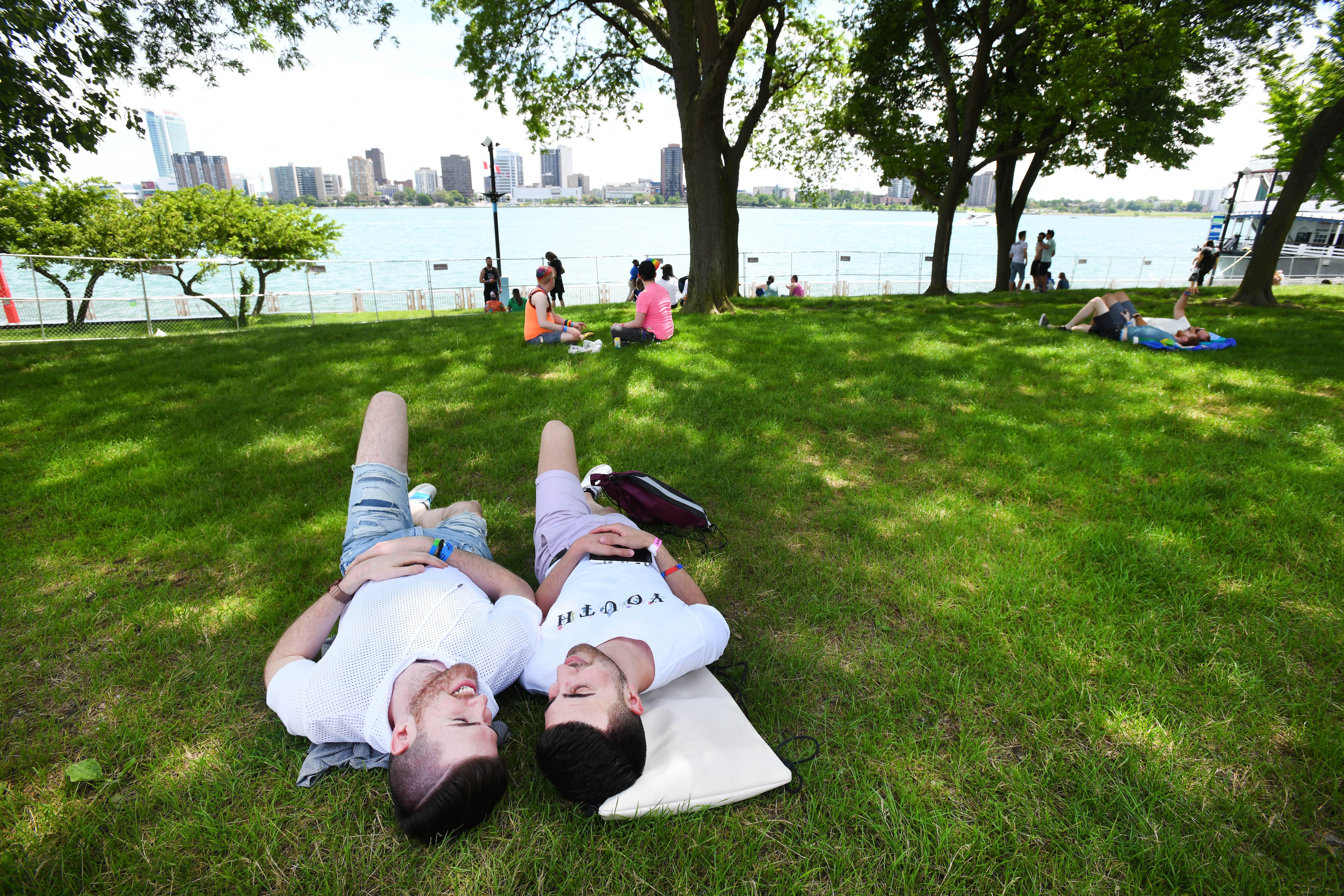 Claudio Martini and Sam Shehedeh relax in the shade along the Detroit River during the Motor City Pride festival in Hart Plaza in Detroit, Michigan on Saturday, June 8, 2019.