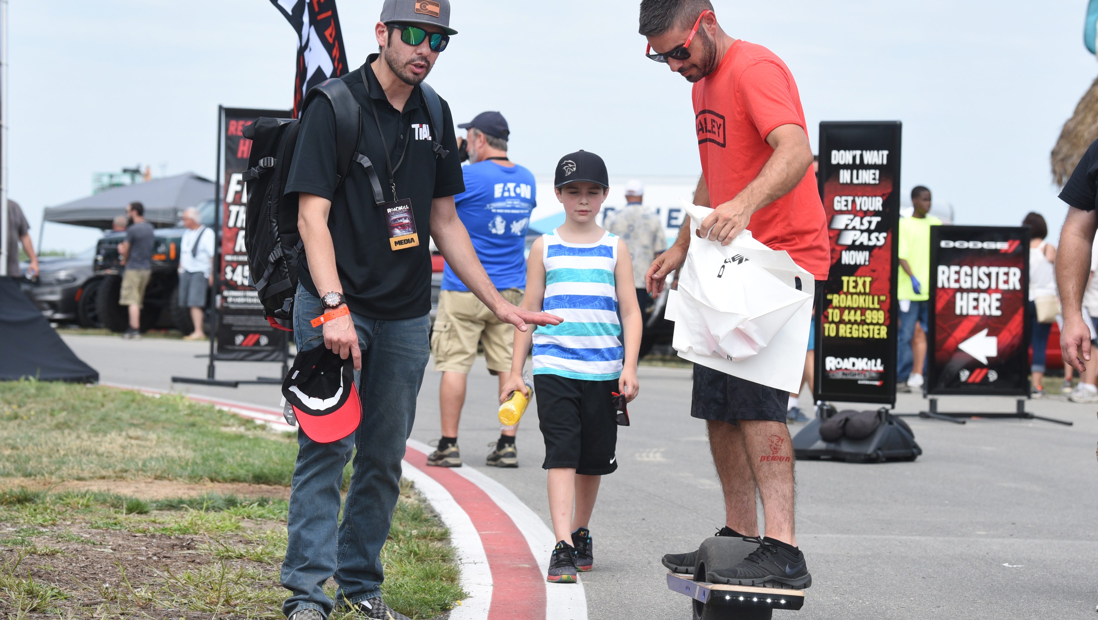 David Elwell (left) helps a fan balance on an electric skateboard called the "one wheel" at the Roadkill Nights held at M1 Concourse in Pontiac on Saturday, August 11, 2018