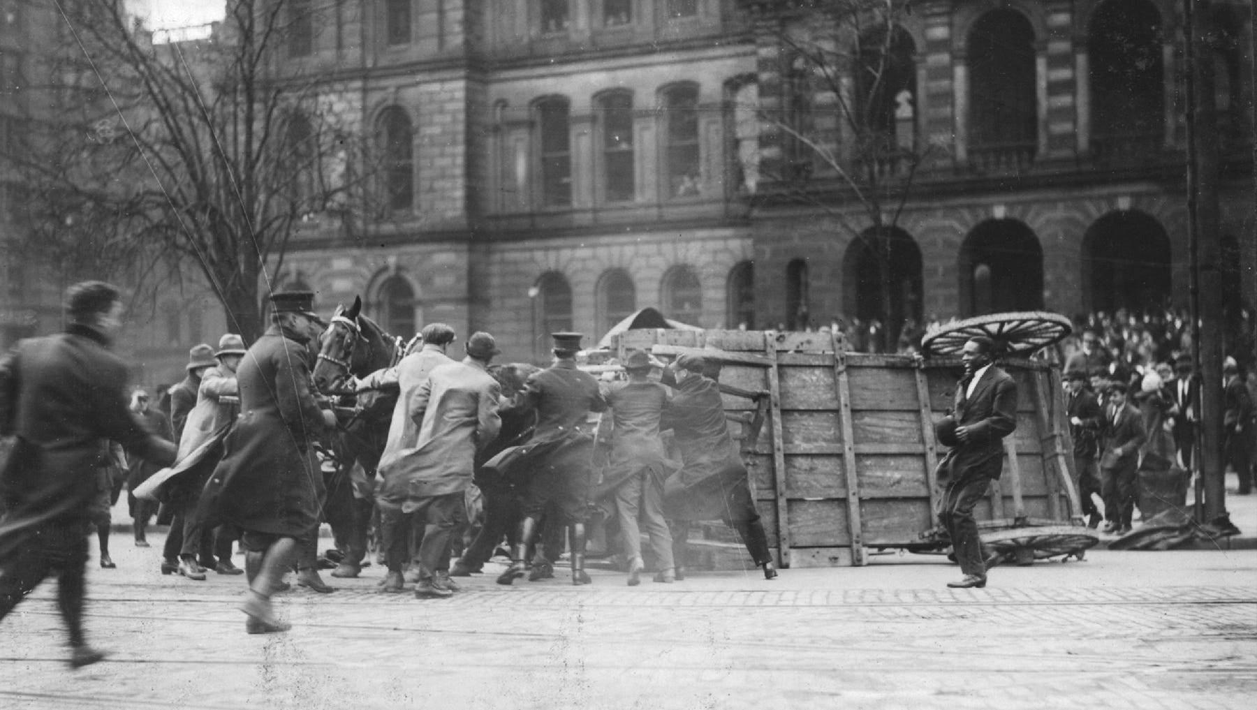 Citizens and police officers in downtown Detroit try to hold horses and flip a wagon that overturned in the high winds. The slow pace of weather reports would contribute to ships being surprised by the ferocity of the storm in the Great Lakes.