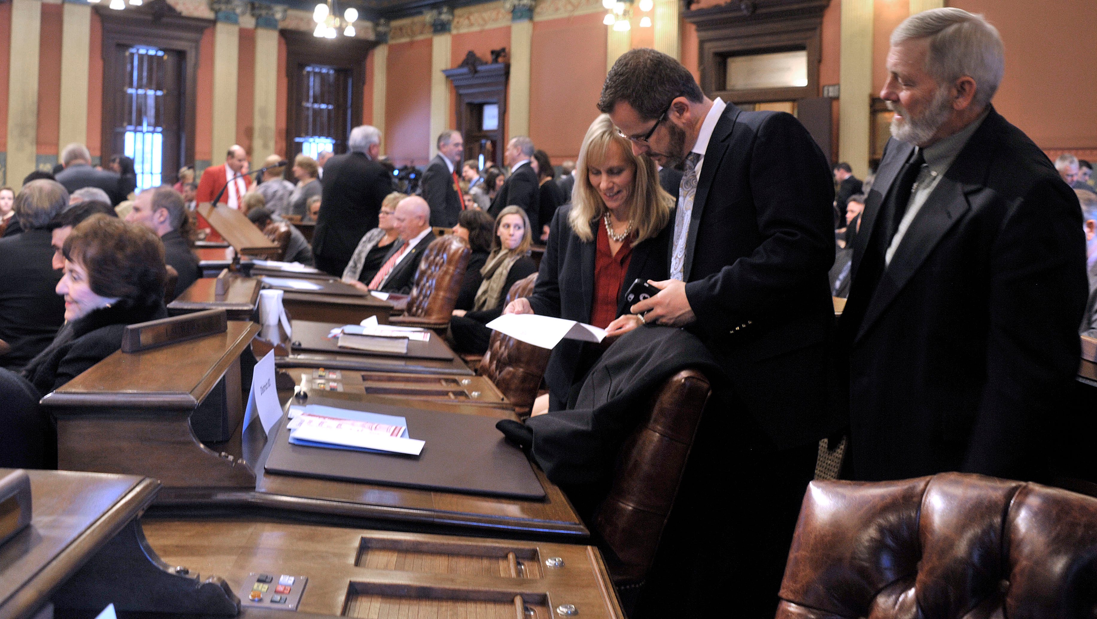 Rep. Cindy Gamrat, R-Plainwell, talks with Rep Todd Courser, R-Lapeer about the location of their new seats. Courser's father, Dan Courser looks over his shoulder.