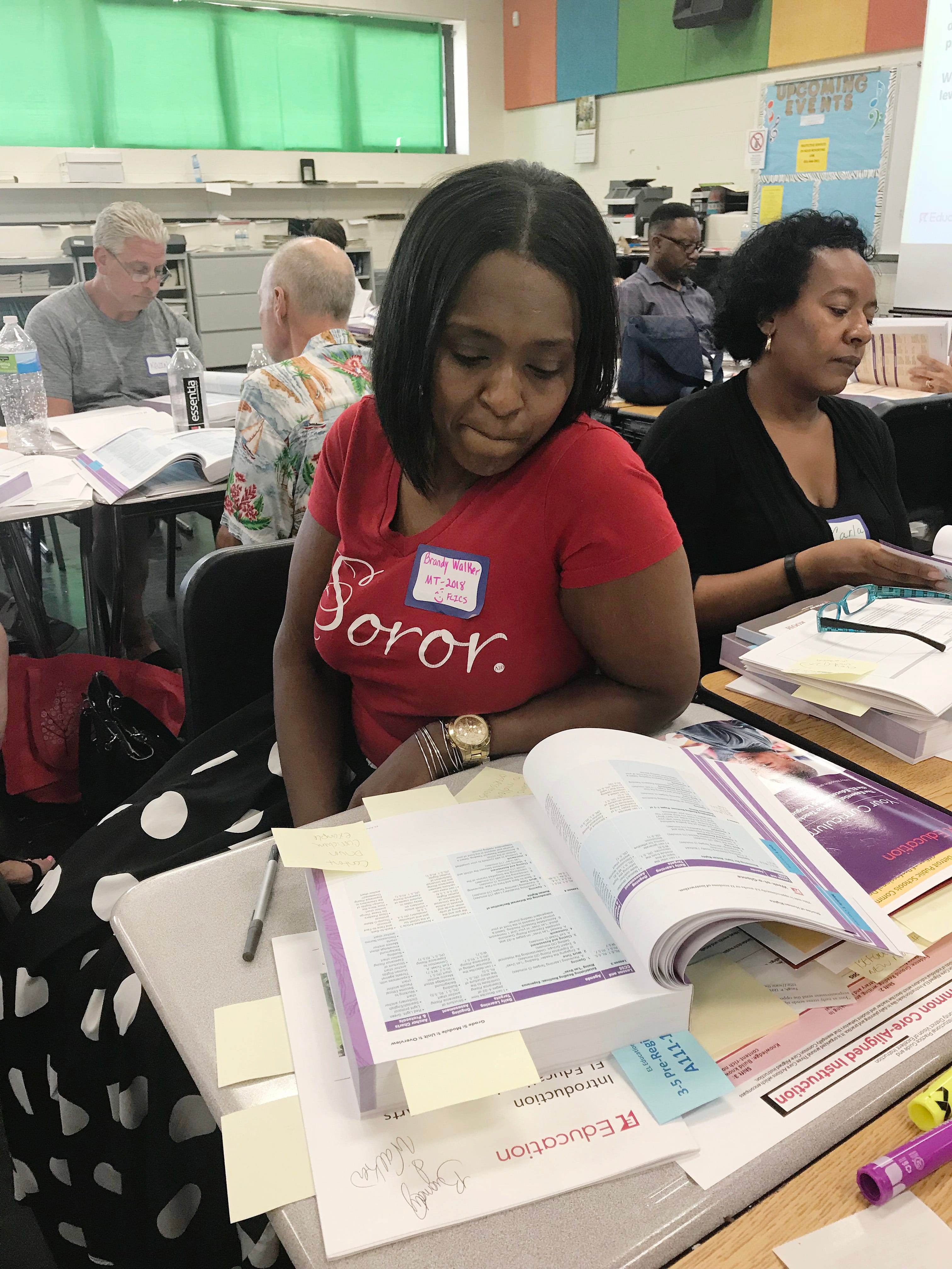 Detroit Public Schools Community District teacher Brandy Walker follows along in a text book during  training on the district’s new curriculum at Martin Luther King Jr. High School in Detroit on July 17, 2018. Walker, a 5th grade reading teacher at the Foreign Language Immersion Cultural Studies school, became a Master Teacher at DPSCD this year. She plans to teach her regular class a half day this school year and use the other half as a master teacher to support the other teachers.