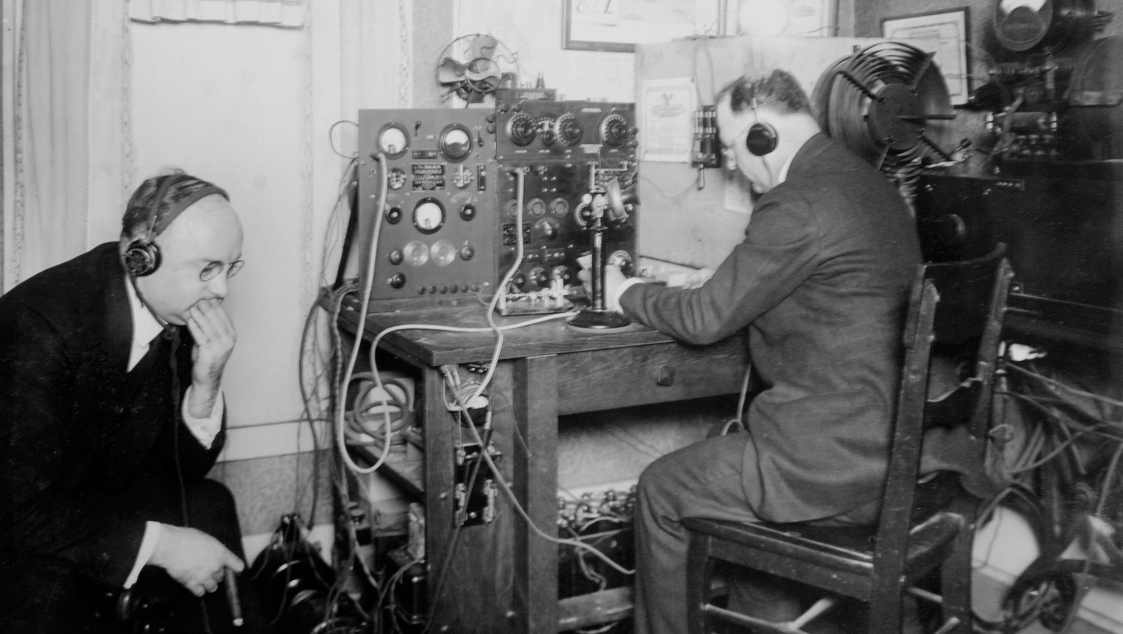 In 1920, Clyde E. Darr, right, handles the controls of his transmitter at 137 Hill Avenue in Highland Park, while Detroit News building superintendent W.E.McGuire, left, listens. It was one of several experiments before The Detroit News would become the first newspaper to have its own radio station, which it set up in a quiet corner of its building.