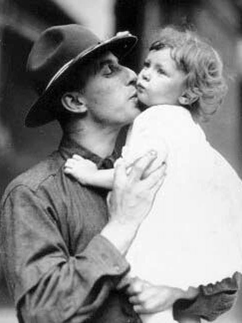 A father drafted into World War I kisses his child goodbye at the train station in Detroit.