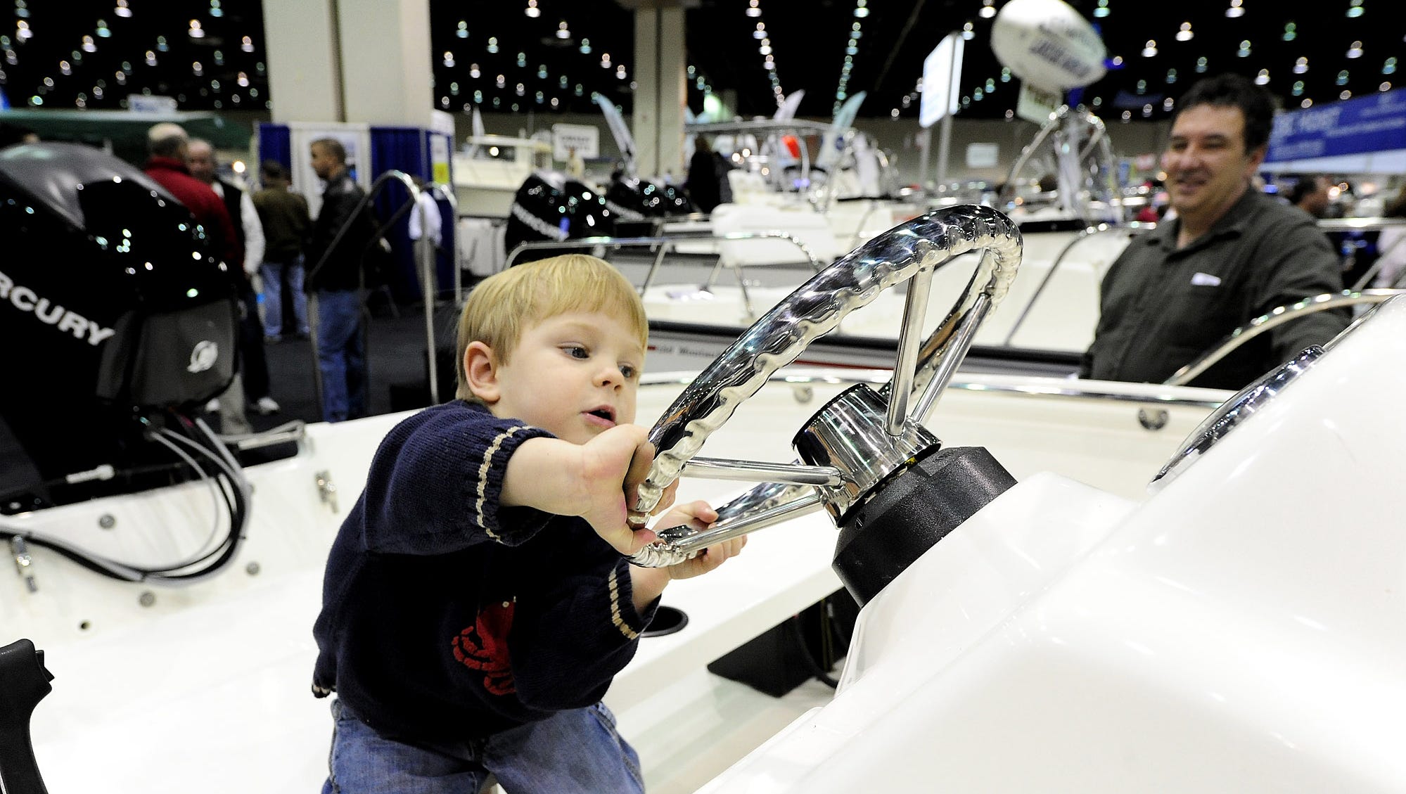 William Osborn of Flushing, 2, takes over the helm under the watchful eyes his grandfather Tim Martenies of Waterford during the 52nd Annual Boat Show at Cobo Center on Feb. 13, 2010.