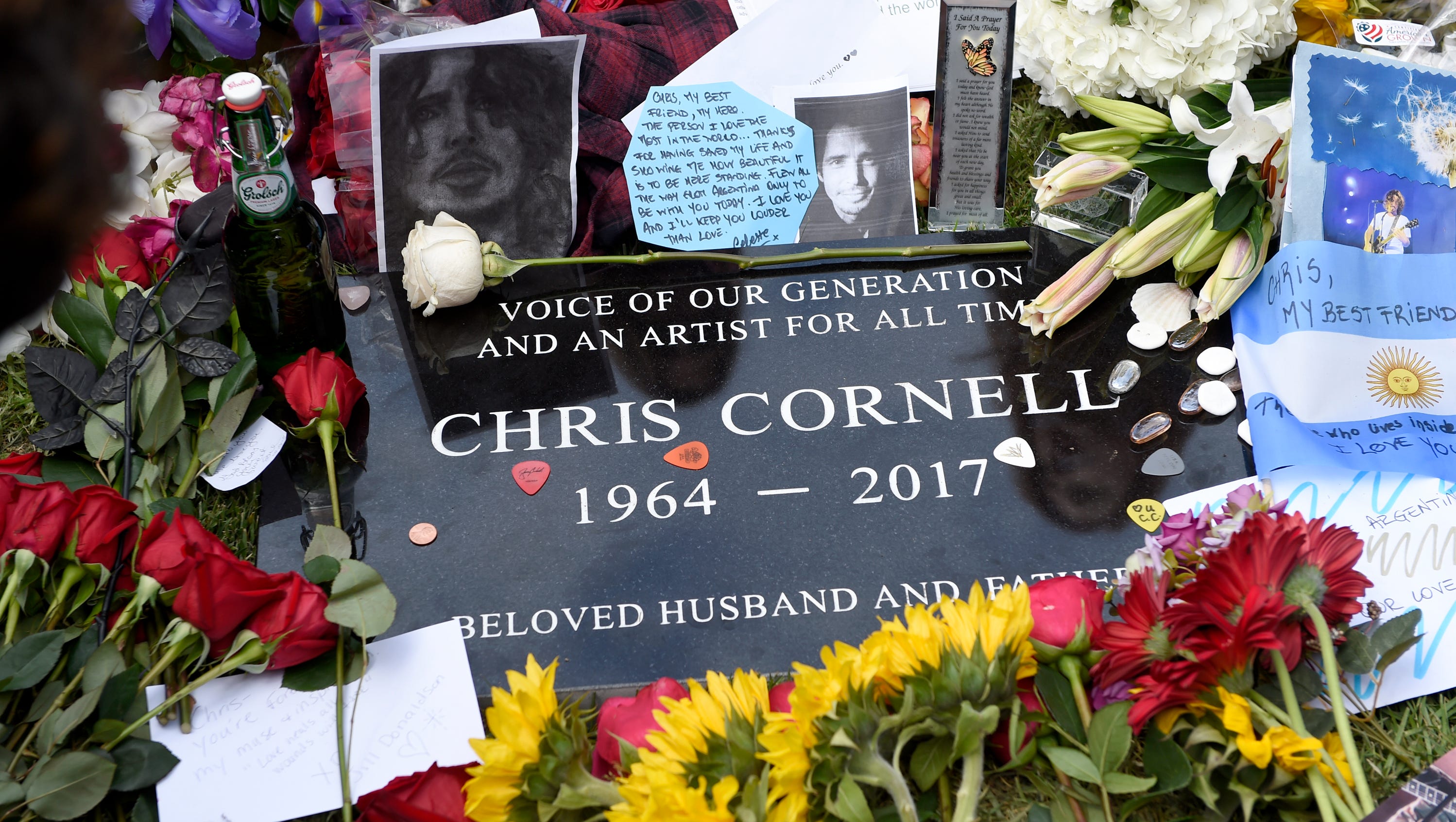 A plaque marking Chris Cornell's gravesite appears, covered in guitar picks, flowers, photos and notes, following the late singer's funeral at the Hollywood Forever Cemetery on Friday, May 26, 2017, in Los Angeles.