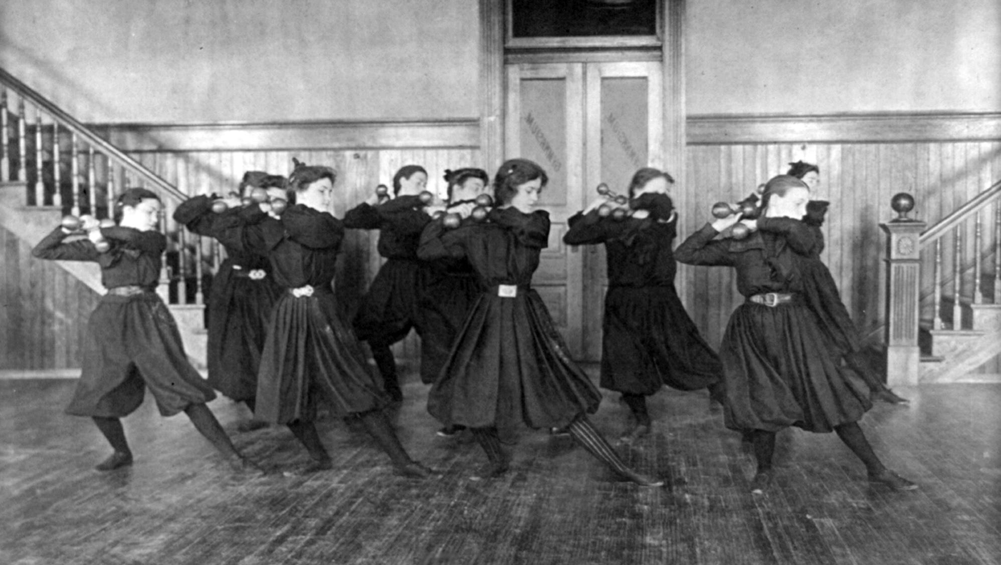Girls work out with dumbells in a high school gym class in 1899.