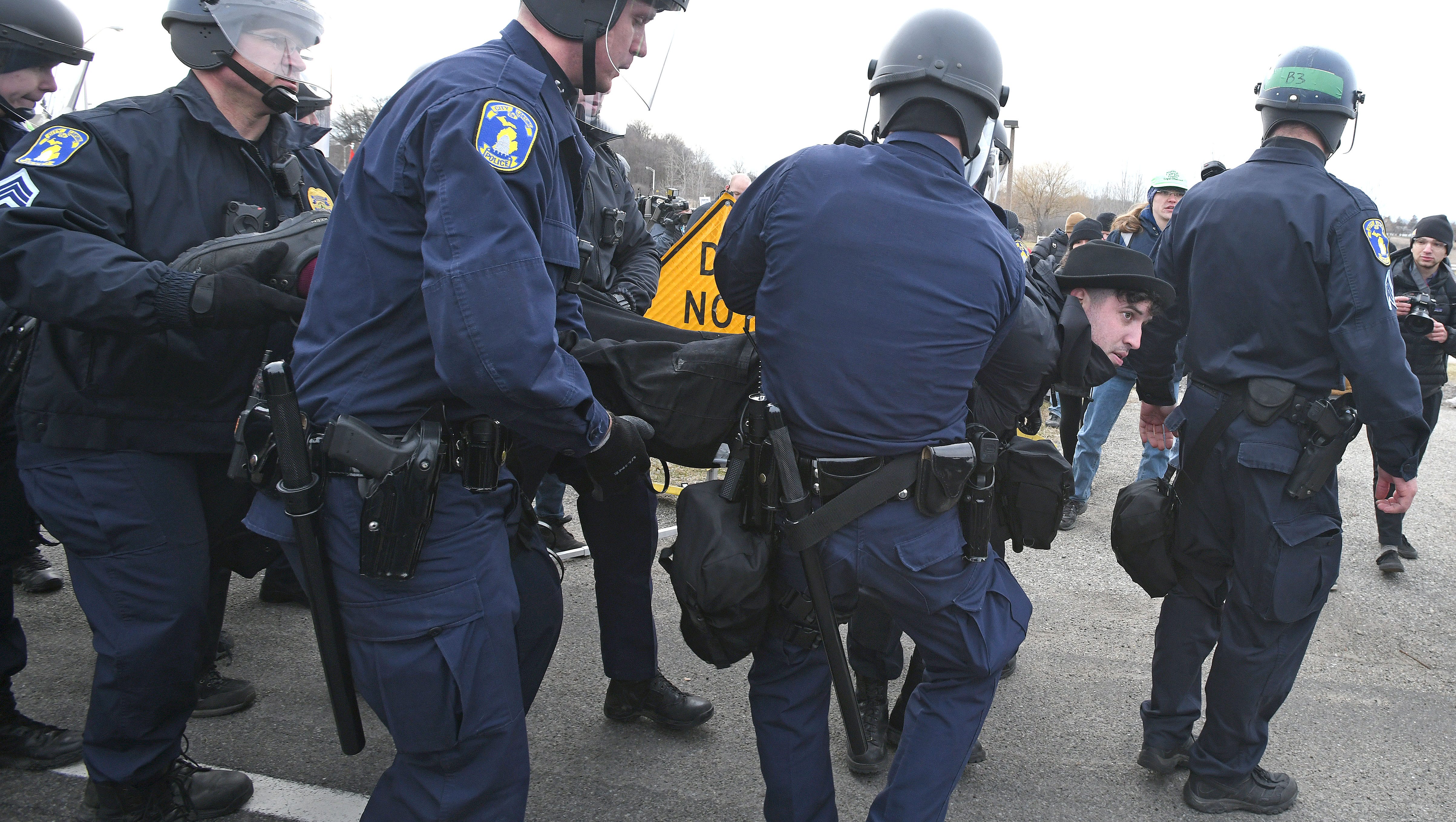A protester is arrested and carried away for blocking a police vehicle outside the MSU Pavilion.