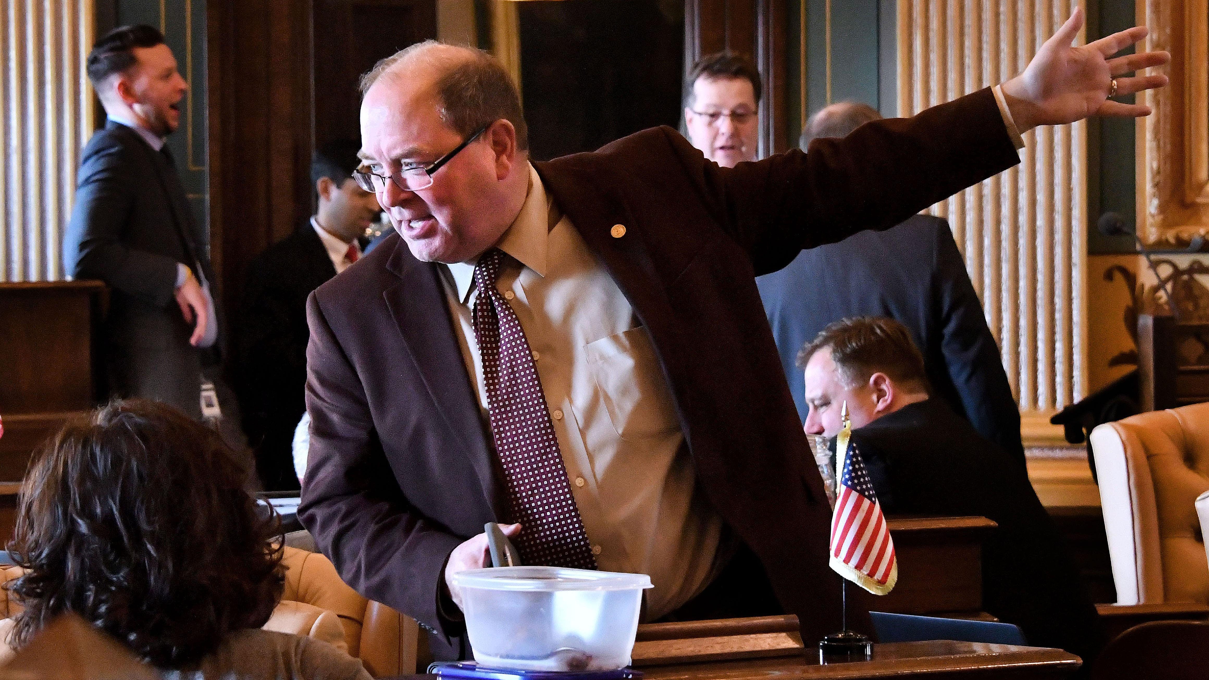 An animated Sen. David Robertson, R-Grand Blanc, waves his hands while talking with collegues as the Michigan Senate deliberated over a package of bills that would change auto fees and increase personal tax exemptions in the state on Wednesday.