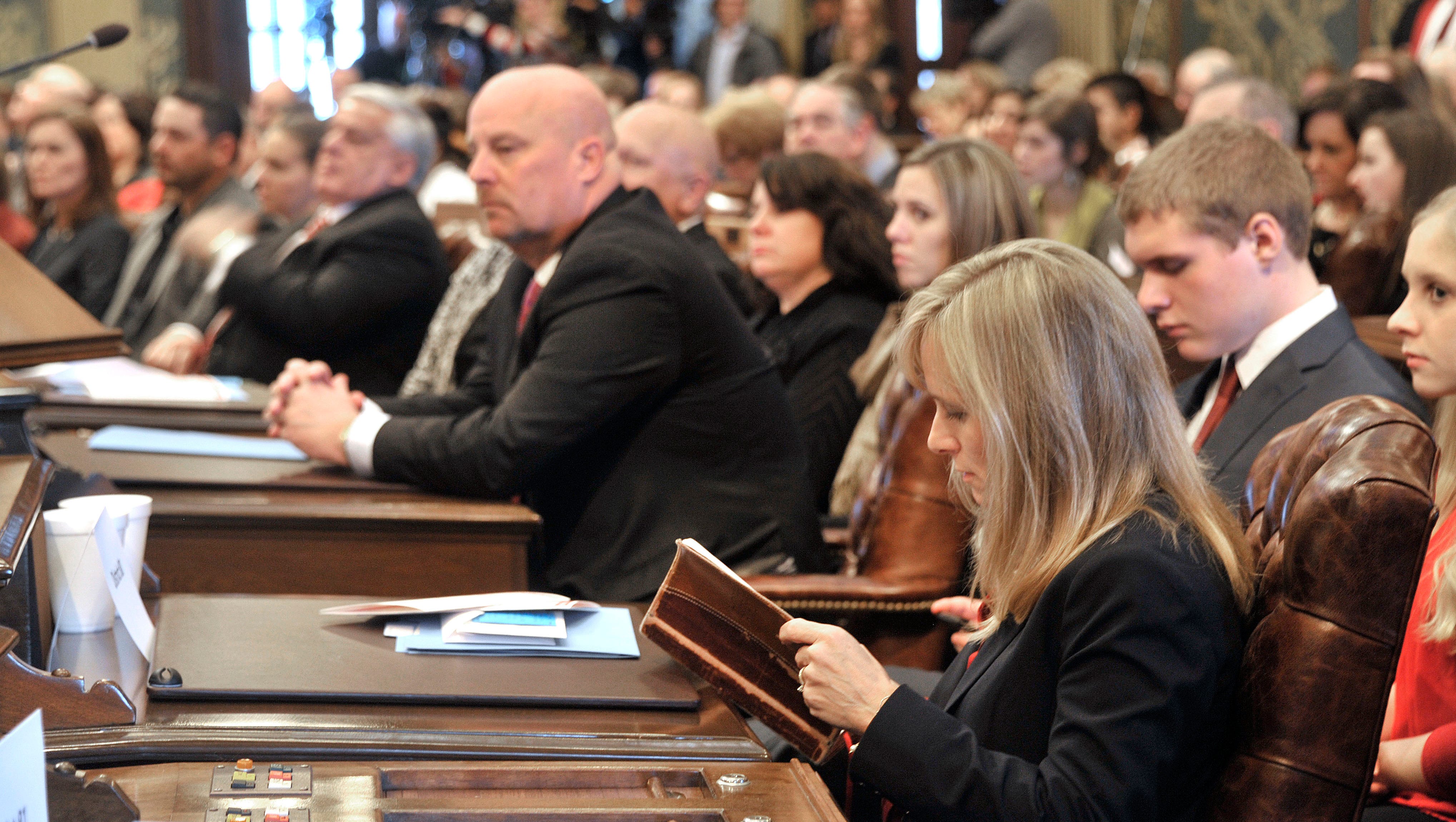 Rep. Cindy Gamrat, R-Plainwell, reads the Bible in her temporary seat while waiting for her turn to select her permanent seat.