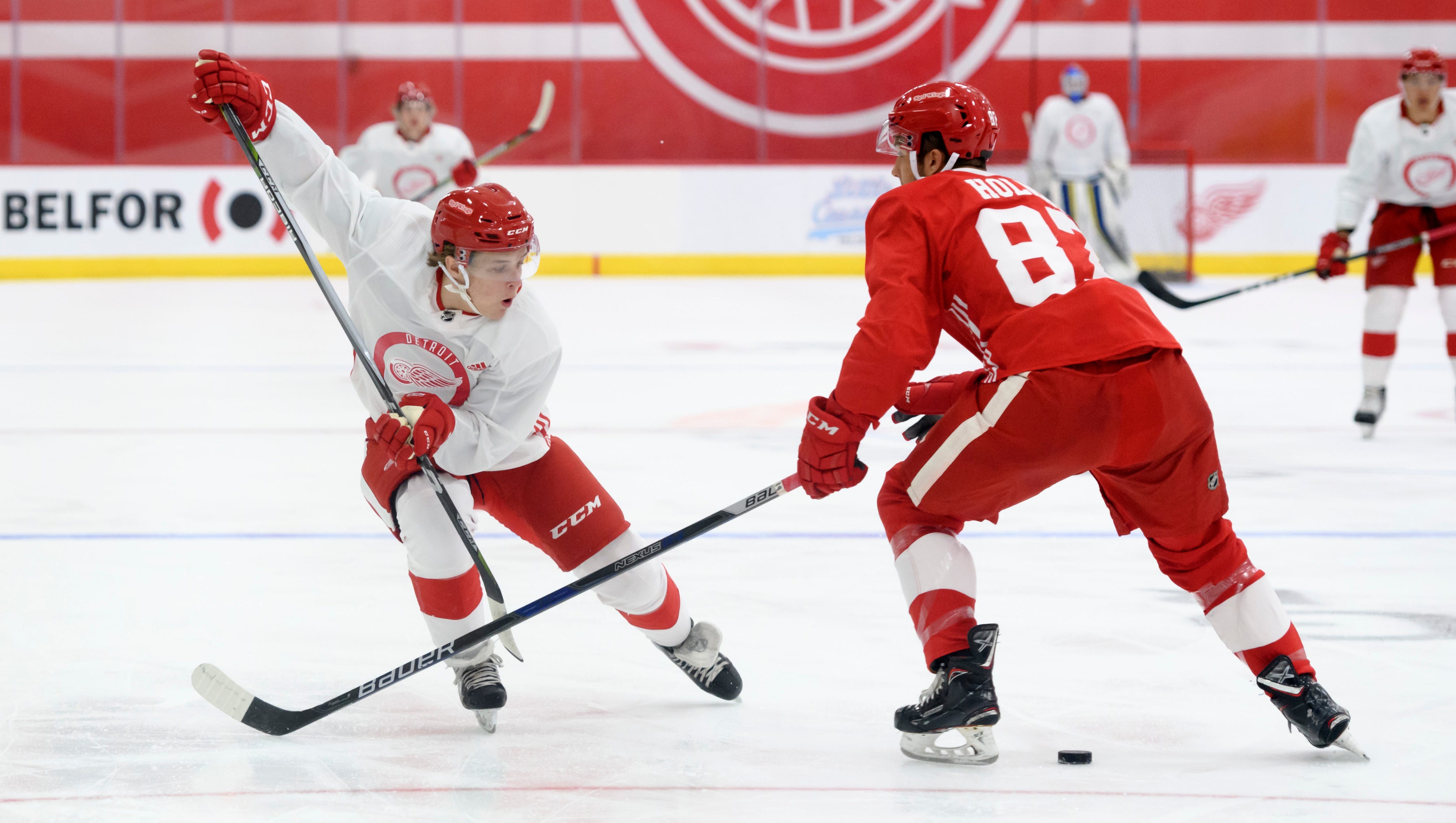Right wing Jonatan Berggren, left, slips the puck around defenseman Patrick Holway during the first period of a scrimmage during the Detroit Red Wings development camp at Little Caesars Arena, in Detroit, June 30, 2018.