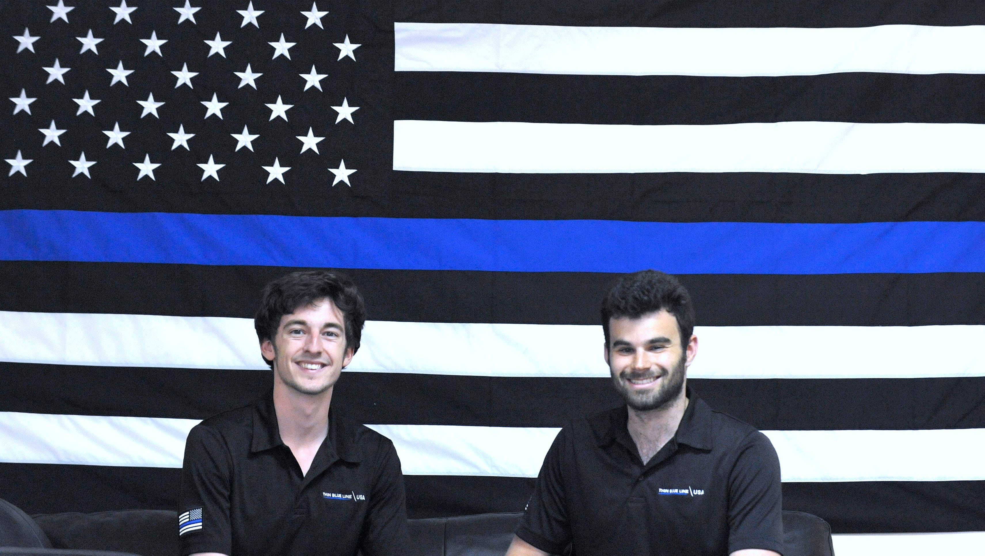 Thin Blue Line  vice president Pete Forhan, 21, left, and president and founder Andrew Jacob, 22, both of Ann Arbor, pose in front of a 5-foot by 8-foot TBL USA flag in the lobby. The two became friends at West Bloomfield High School. Now they sell police, fire, dispatcher, corrections officers, EMS and other first responders hats, patches, wrist bands and apparel from their Ann Arbor shipping center.