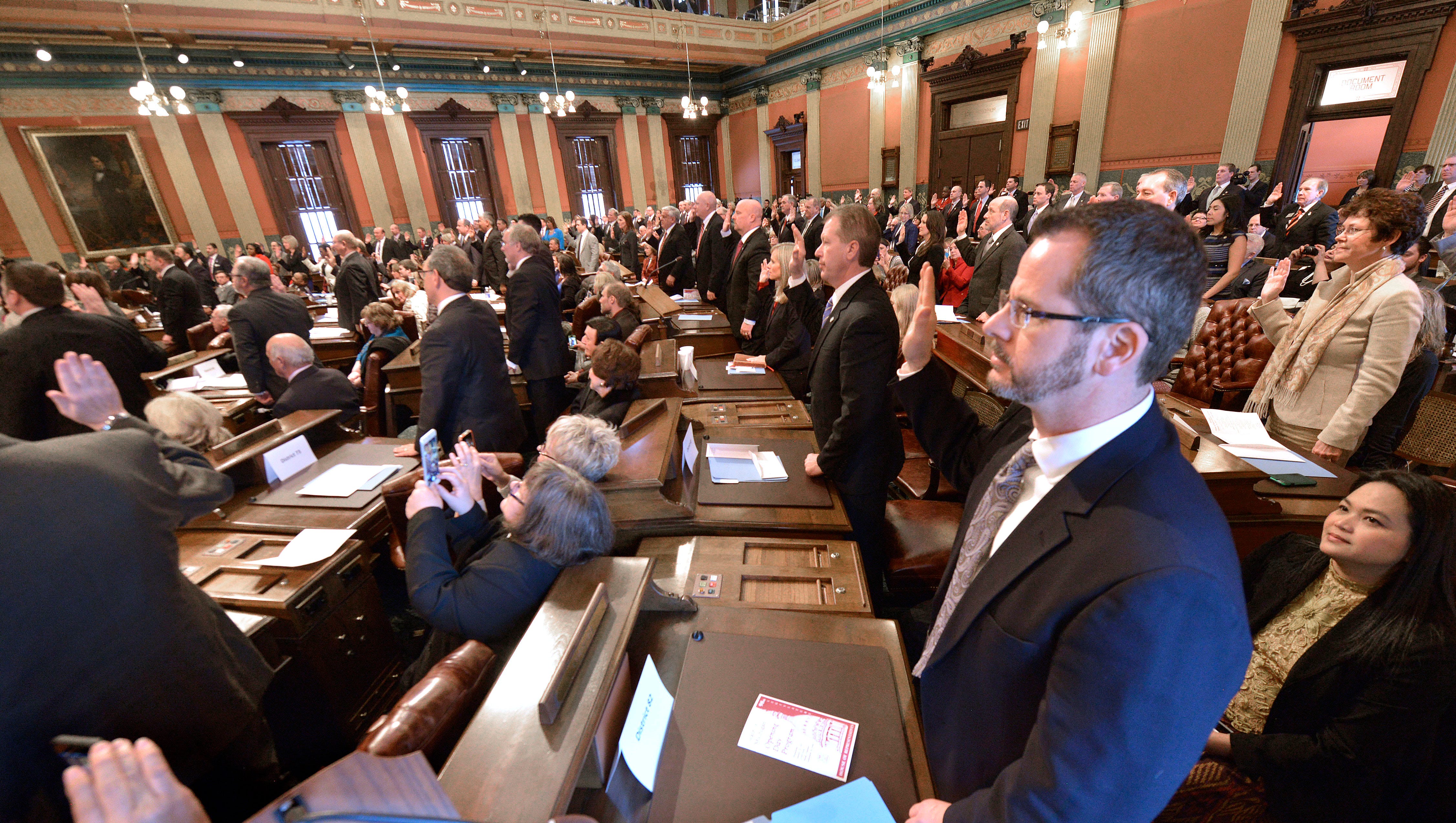 Rep. Todd Courser, R-Lapeer, takes his oath of office with his peers in the House of Representatives on the Michigan Legislature's first day of the new session, Wednesday, Jan. 14, 2015, in Lansing.  Seated behind Rep. Courser is his wife, Fon Courser.