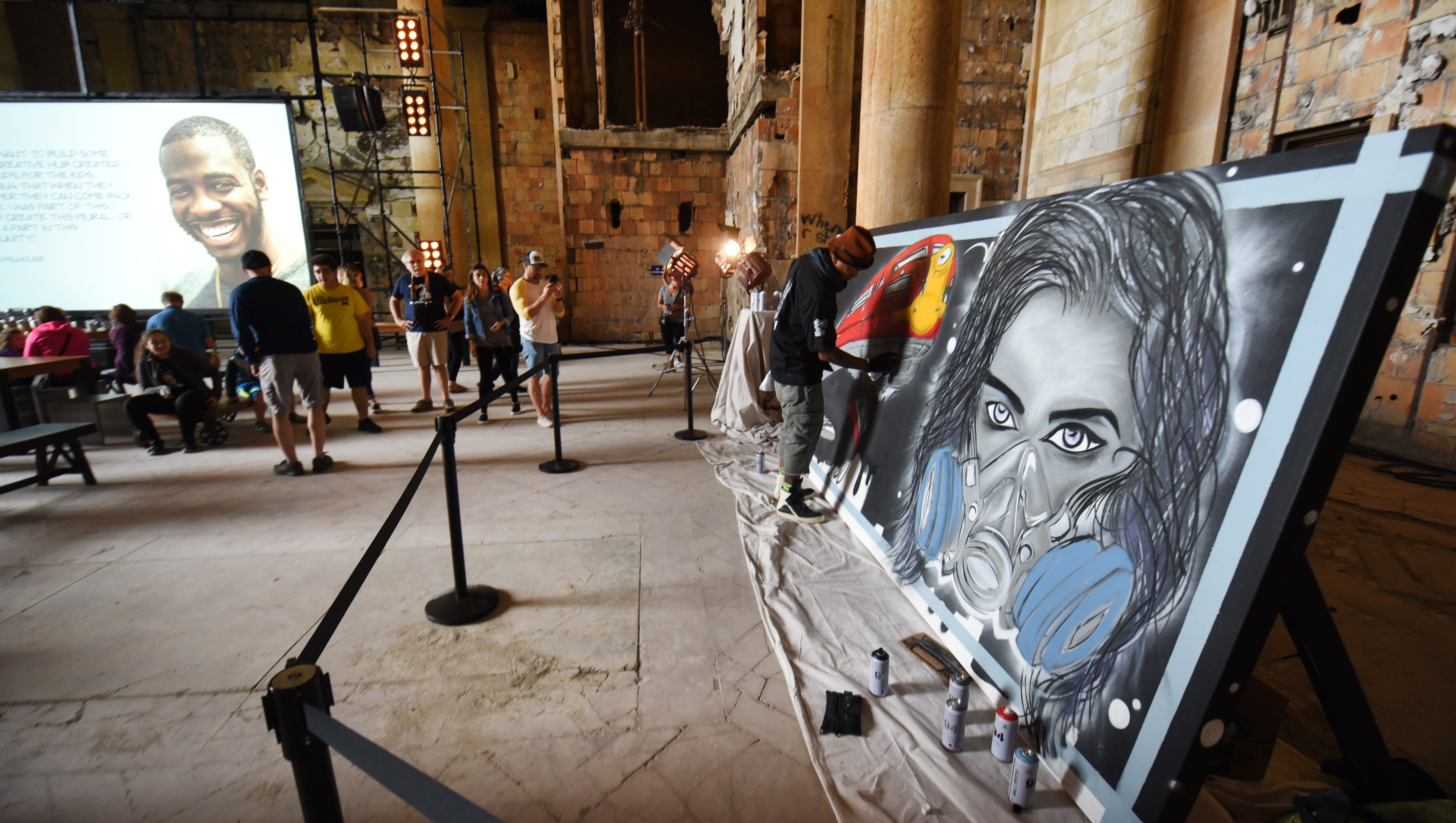 Detroit artist Antonio "shades" Agee spray-paints his latest project for the crowd at the Michigan Central Train Depot.