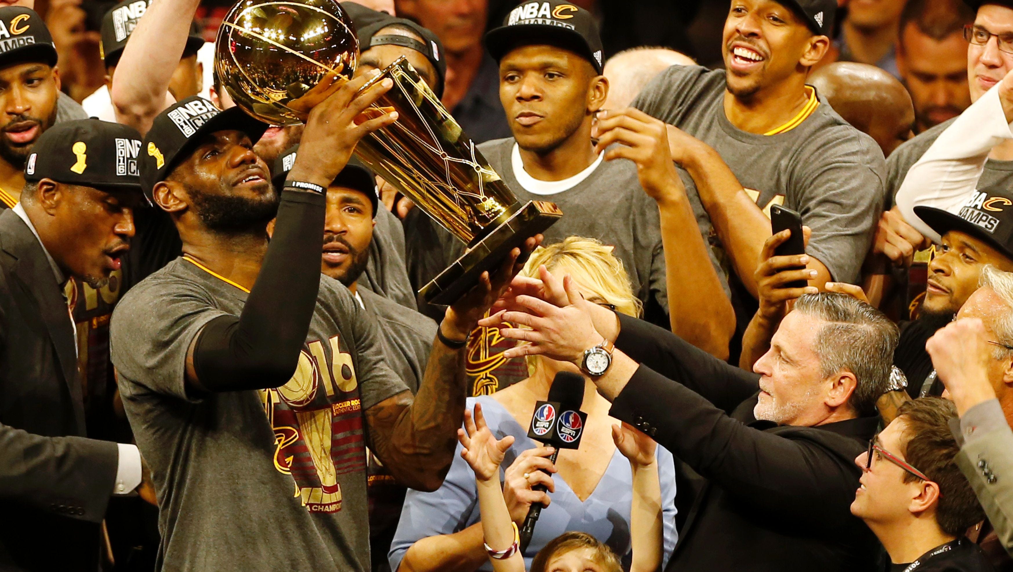 Cavaliers forward LeBron James, left, hoists the Larry O'Brien trophy with owner Dan Gilbert, right, after defeating the Golden State Warriors to win the NBA title in Oakland, California.