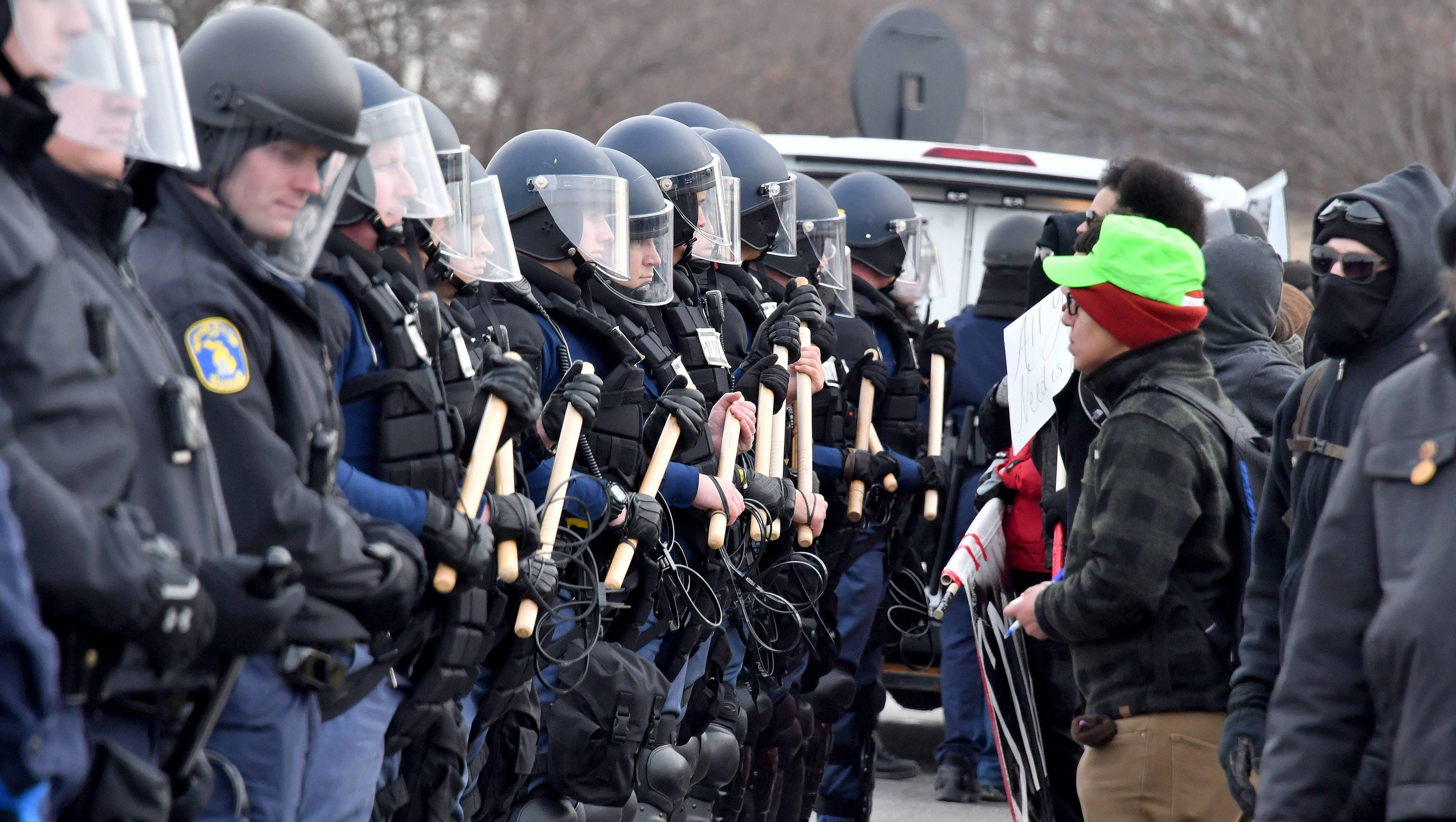 A protester taunts a line of police officers in riot gear.