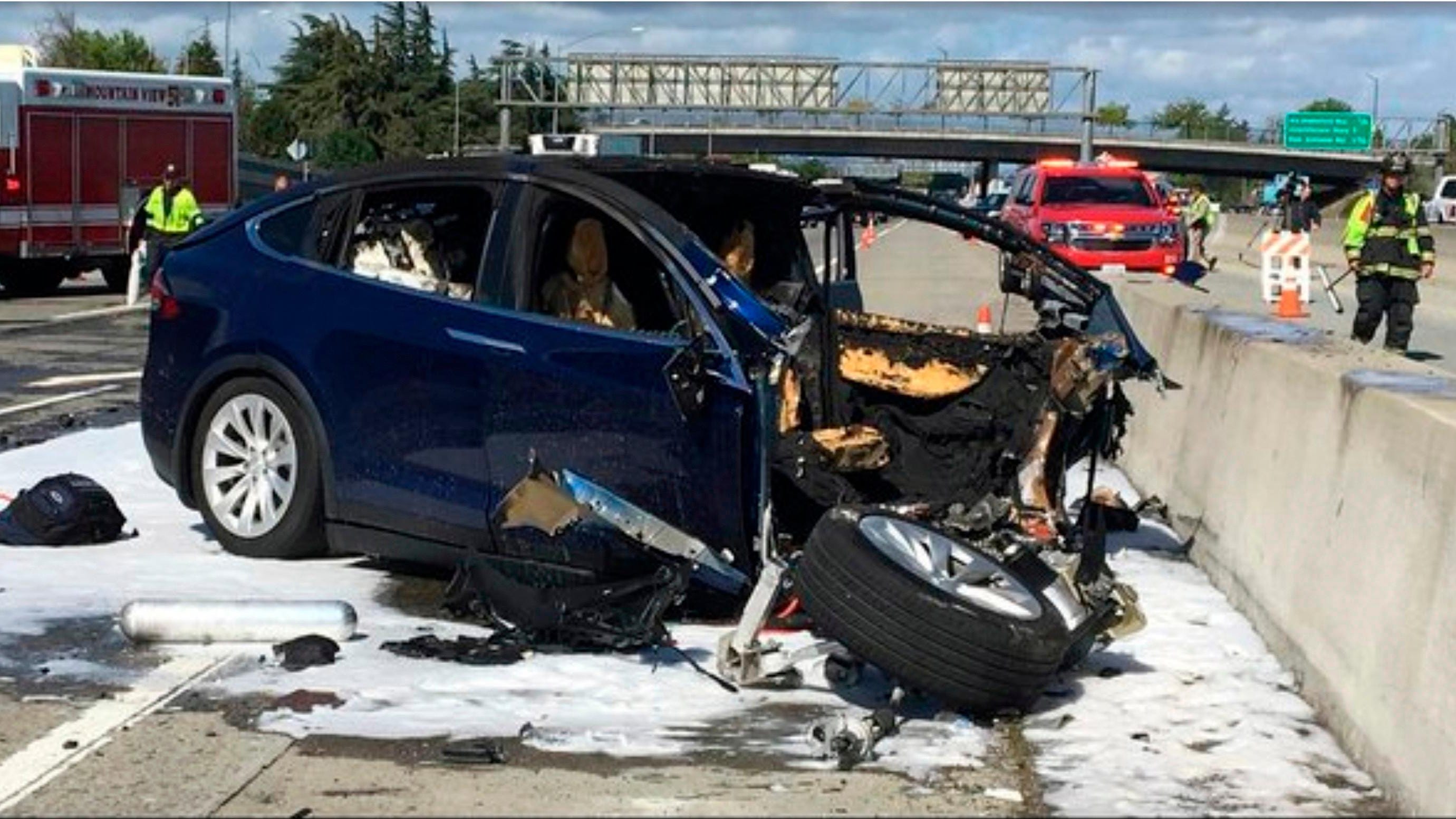 In this March 23, 2018, file photo provided by KTVU, emergency personnel work at the scene where a Tesla electric SUV crashed into a barrier on U.S. Highway 101 in Mountain View, Calif. Federal investigators say the Tesla using the company’s semi-autonomous driving system accelerated just before crashing into a California freeway barrier, killing its driver.