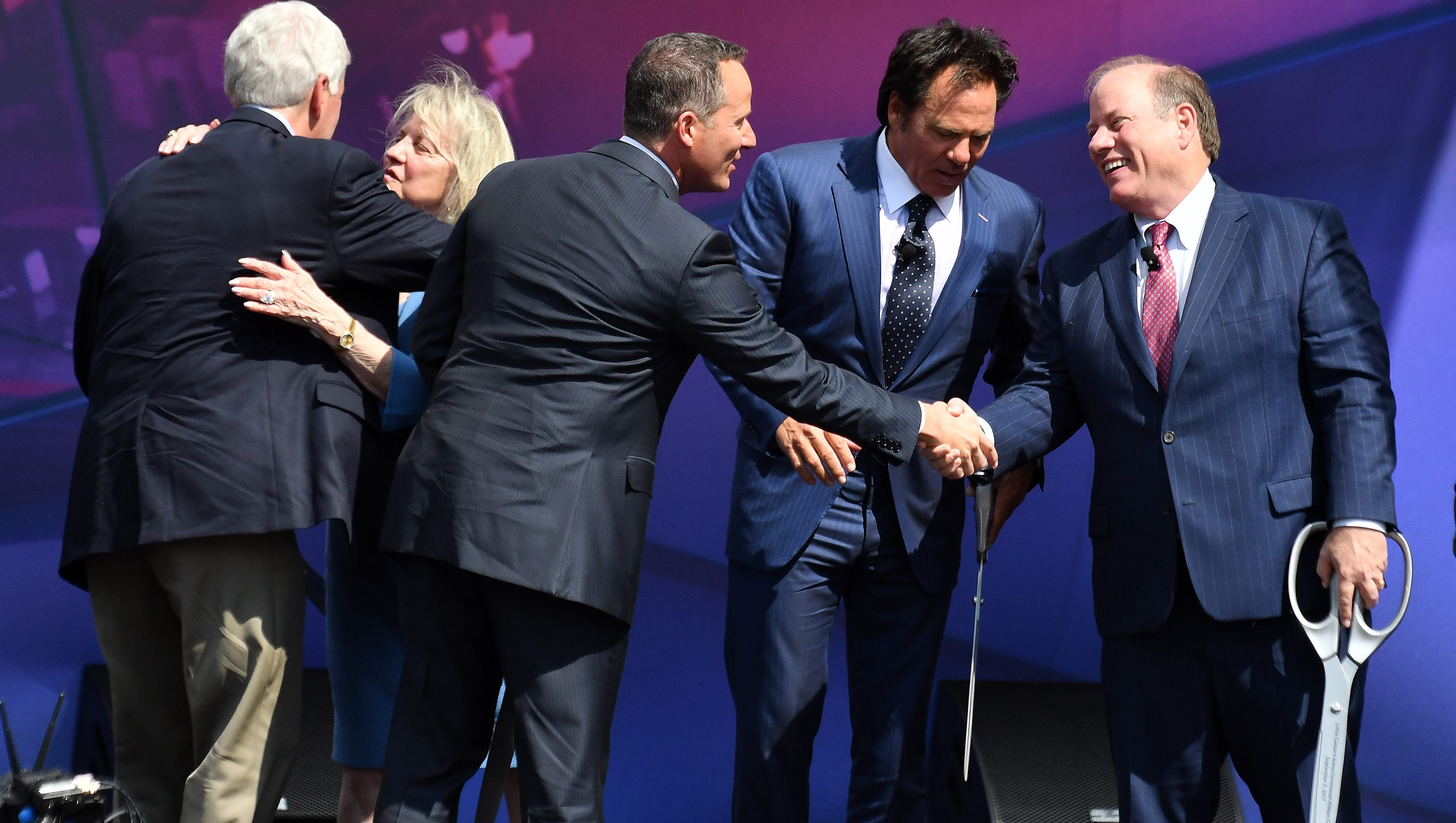Chris Ilitch, center, shakes hands with Detroit mayor Mike Duggan, right, with Tom Gores, Pistons owner, between them, at the ribbon cutting ceremony.