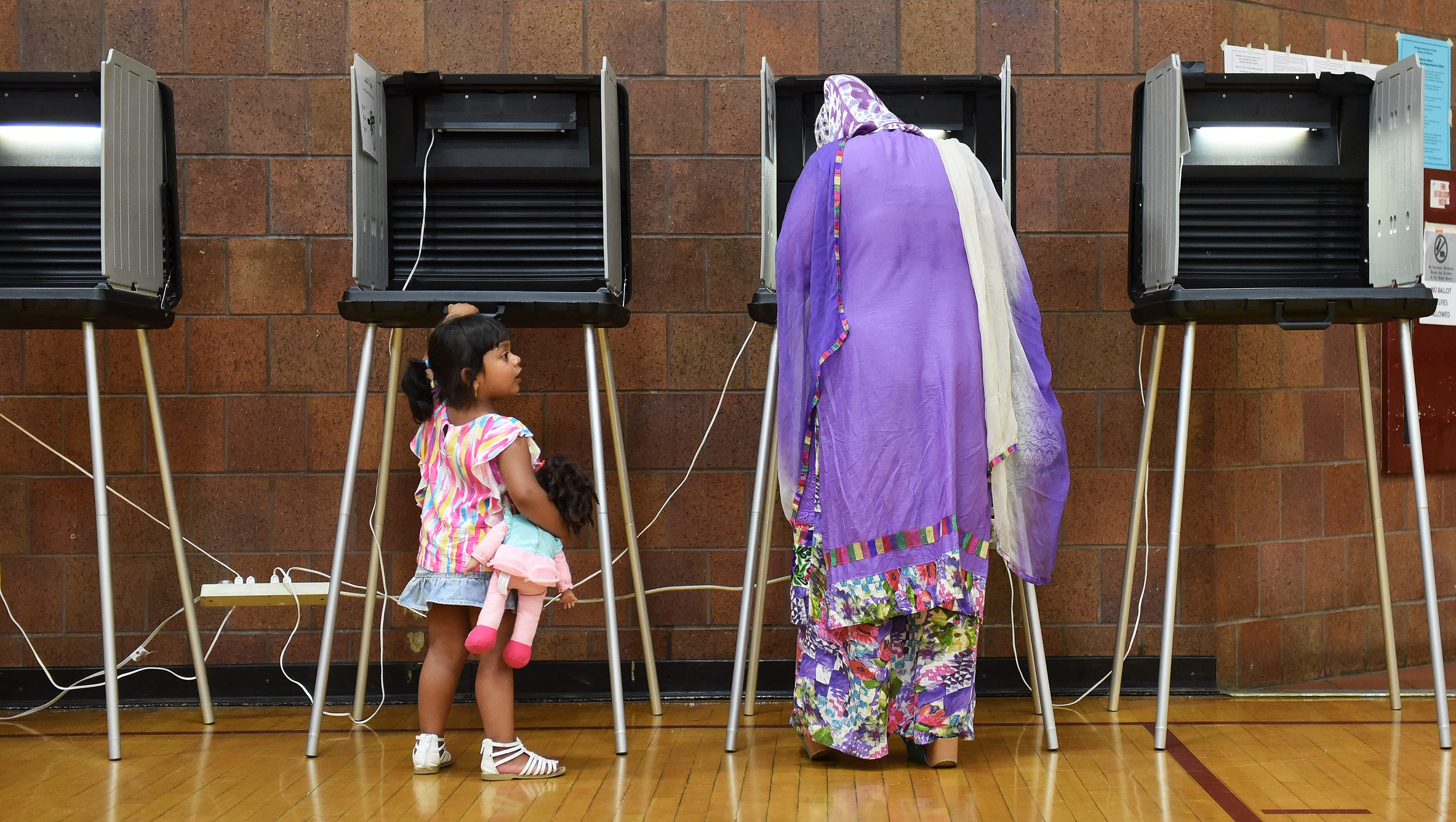 Farnaz Anaum, 3, looks at her mother, Farzana Akhter while she fills out her ballot for precinct 3 at the polling center at Hamtramck High School in Hamtramck, Mich. on Aug. 8, 2017.