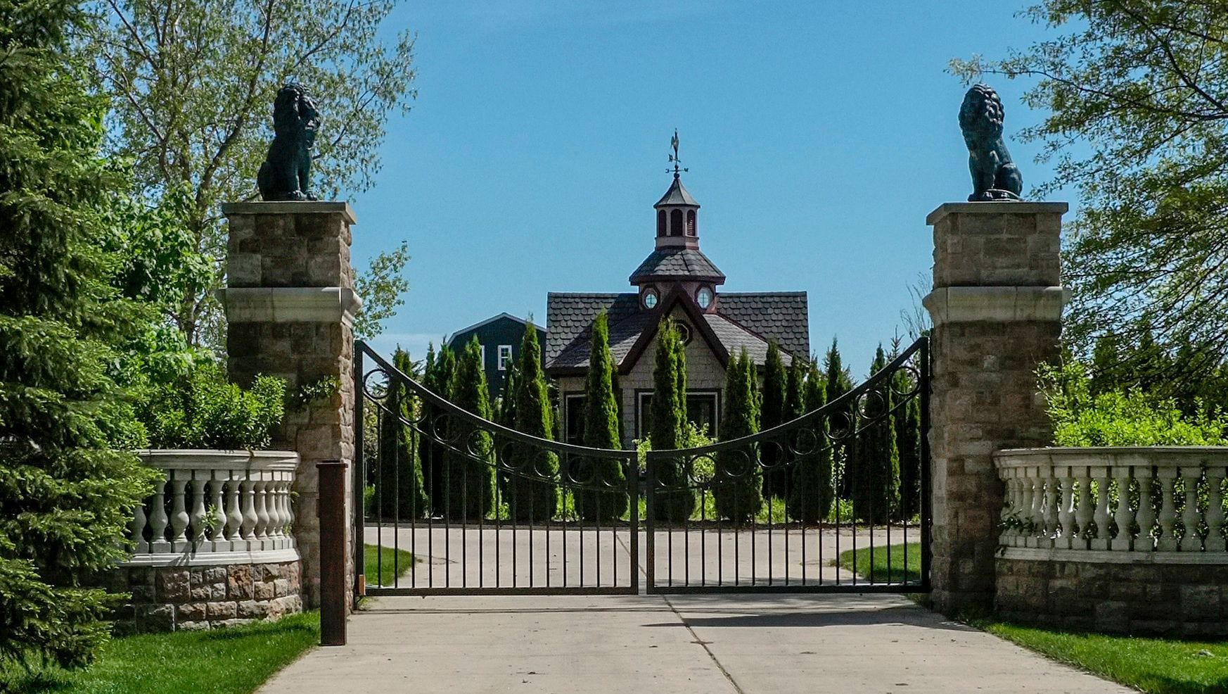 The entrance to the Williamston, Michigan home of the Rev. Jon Wehrle features a gate anchored by two stone columns. The Catholic priest is accused of embezzling $5 million from St. Martha's Church in Okemos over at least 19 years.
