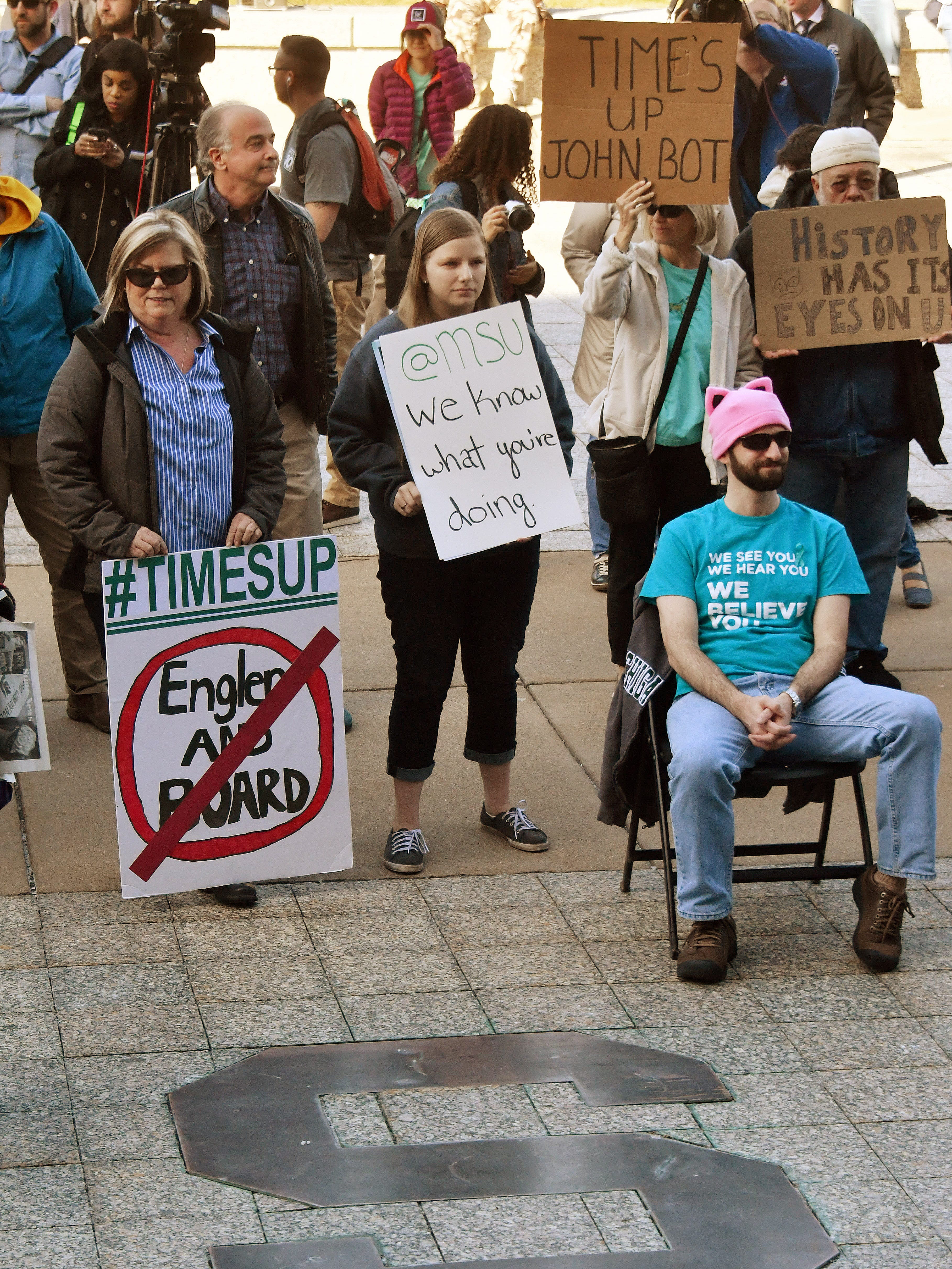 A few signs were scattered around the crowd on Friday, April 20, 2018, as "Reclaim MSU" and some survivors of disgraced sports doctor Larry Nassar rally in front of the Administration Building for the resignations of Michigan State University trustees and Interim president John Engler.