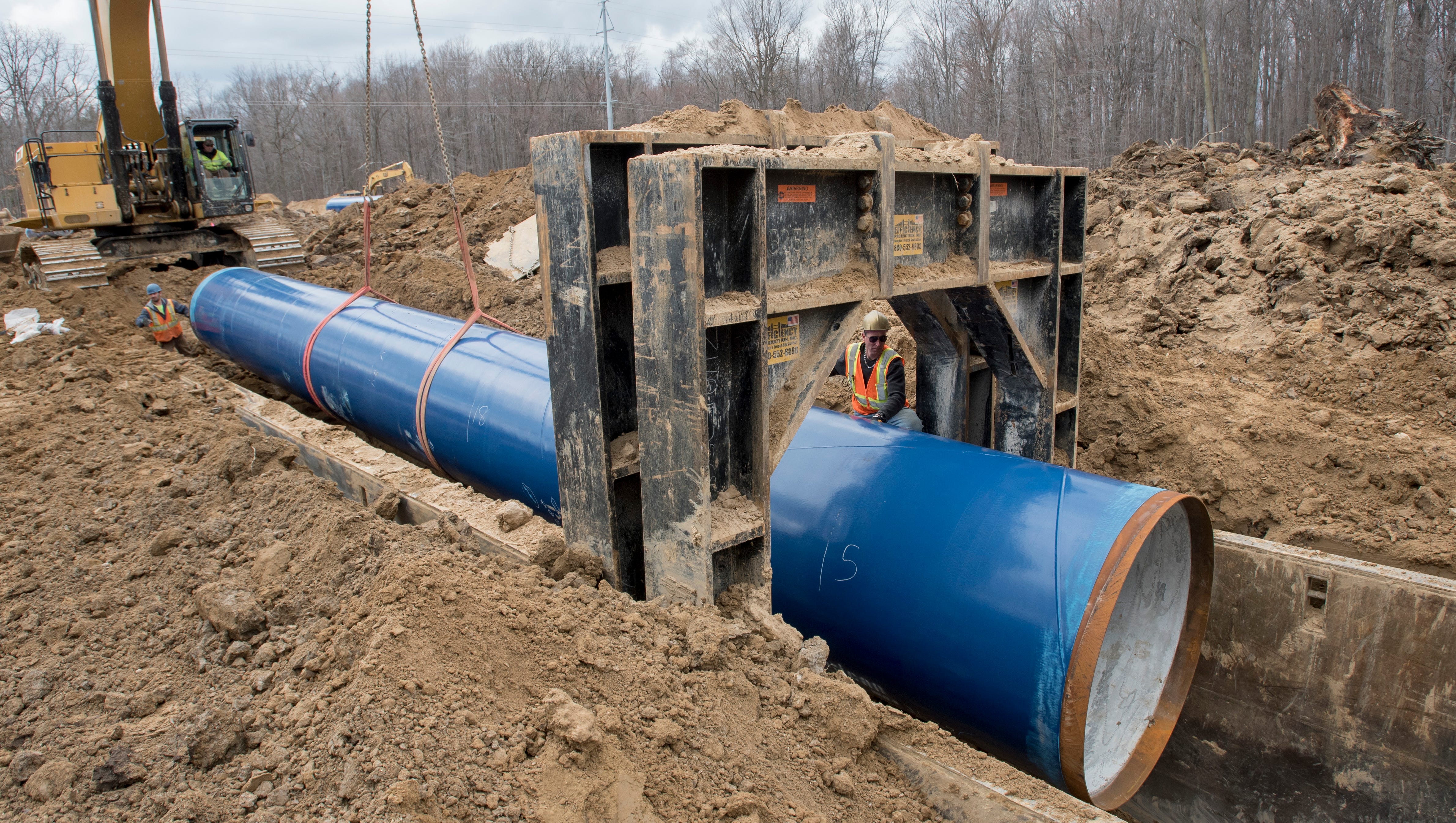 Laborers work on inserting a 50-foot section of the pipeline.