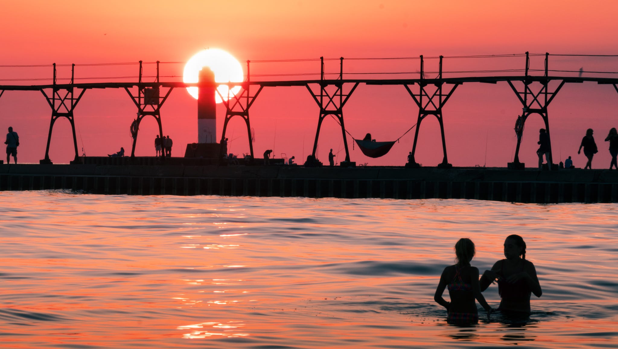 The Grand Haven lighthouse and pier attract all kinds of activities in "Enjoying Day's End," by Paula Buermele of Adrian. "I try to capture the sense of family and friends in my photos ... and who can resist a sunset?" she said.