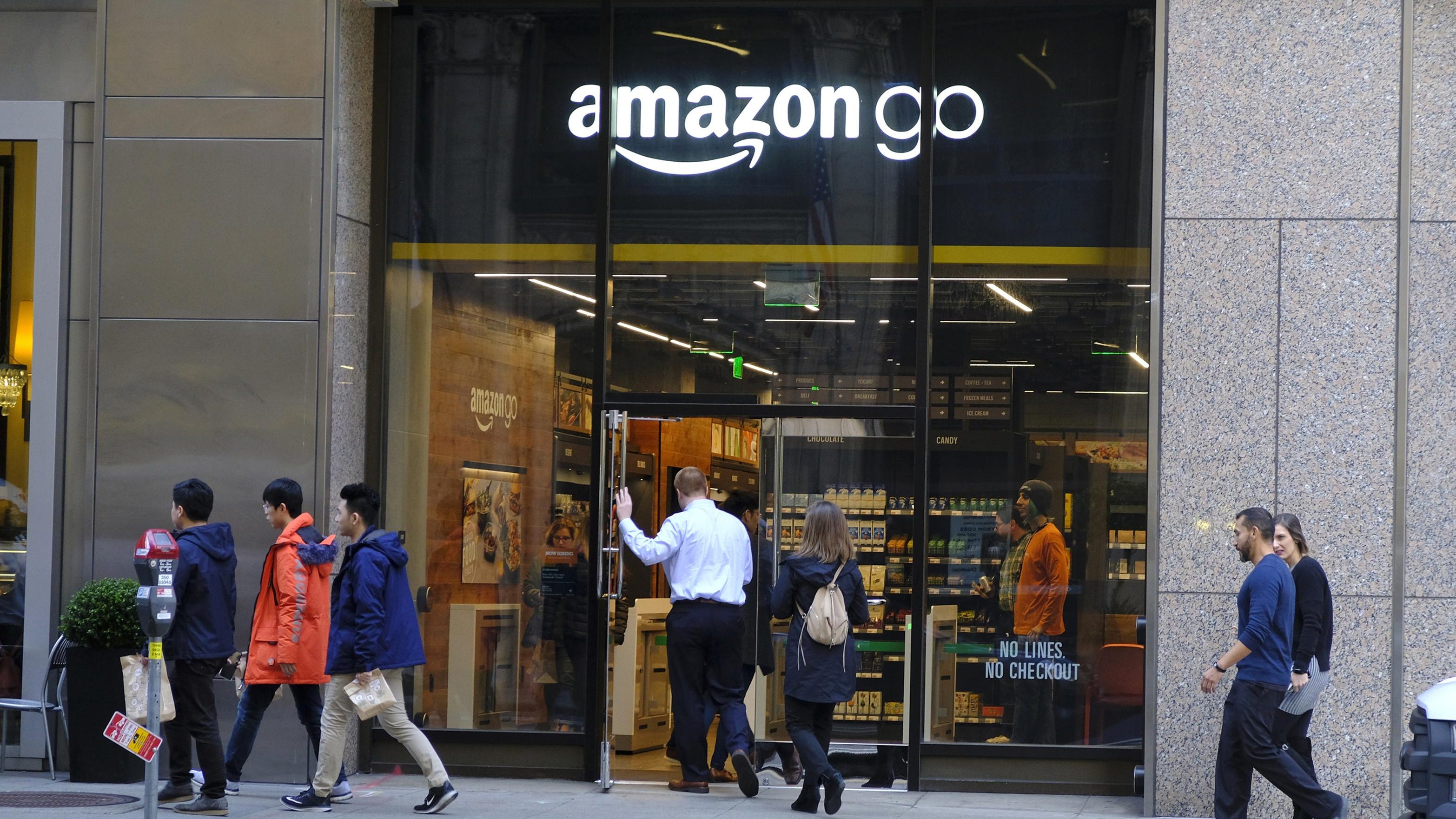 In this Jan. 30, 2019, file photo people walk past and into an Amazon Go store in San Francisco. Amazon, facing backlash from critics who say cashless stores discriminate against the poor, will soon accept cash at all its stores. The online shopping giant has more than 30 stores that don’t accept cash, including its book shops and Amazon Go convenience stores.