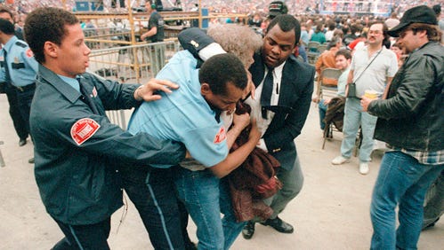 An unruly wrestling fan is escorted out of the building by Silverdome security.