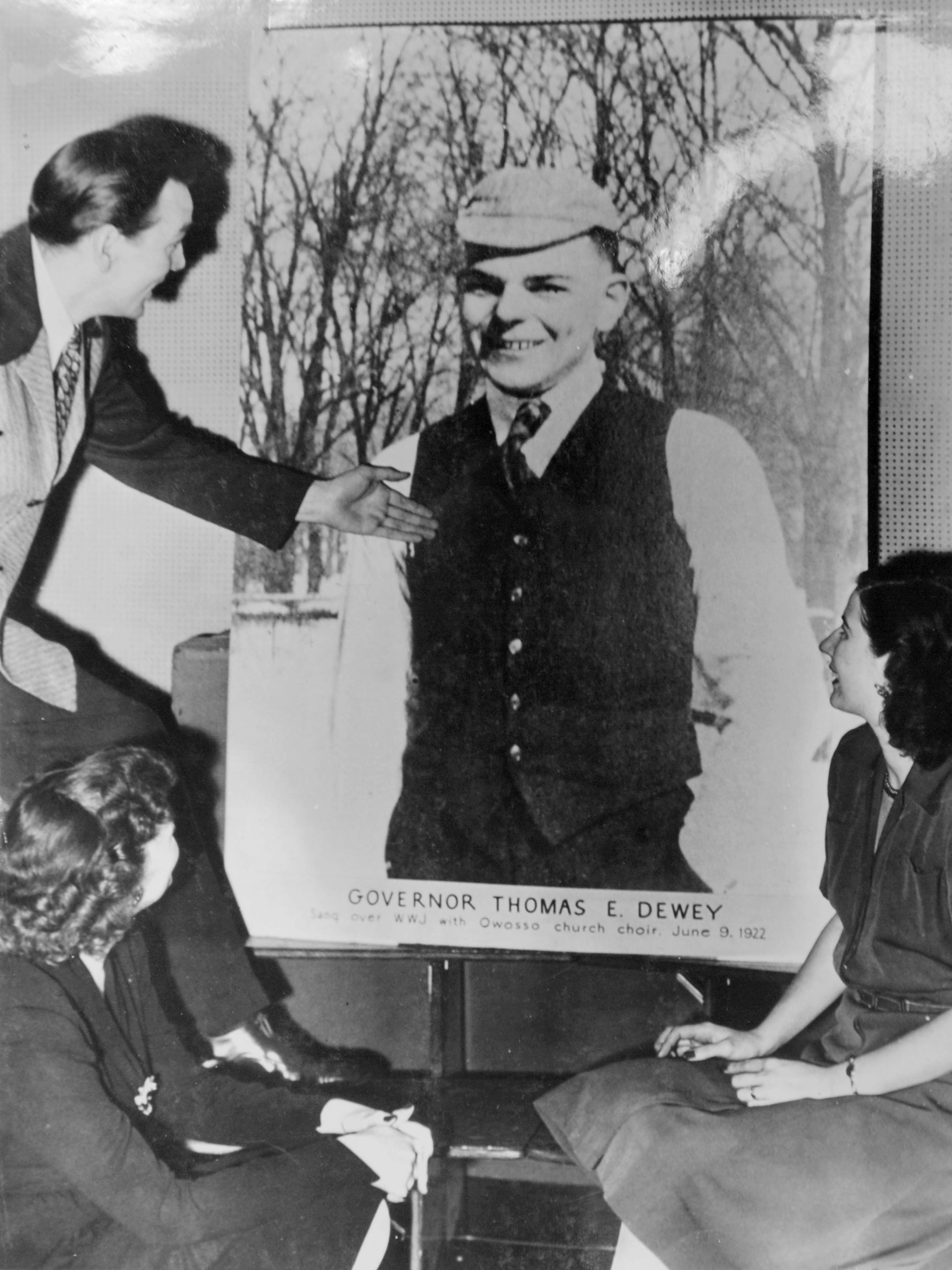 In this undated photo, people look at a vintage poster of Thomas E. Dewey, the governor of New York and Republican presidential candidate in 1944 and 1948. Dewey was a native of Owosso, Michigan, and, as the poster notes, sang over WWJ with an Owosso church choir in 1922.