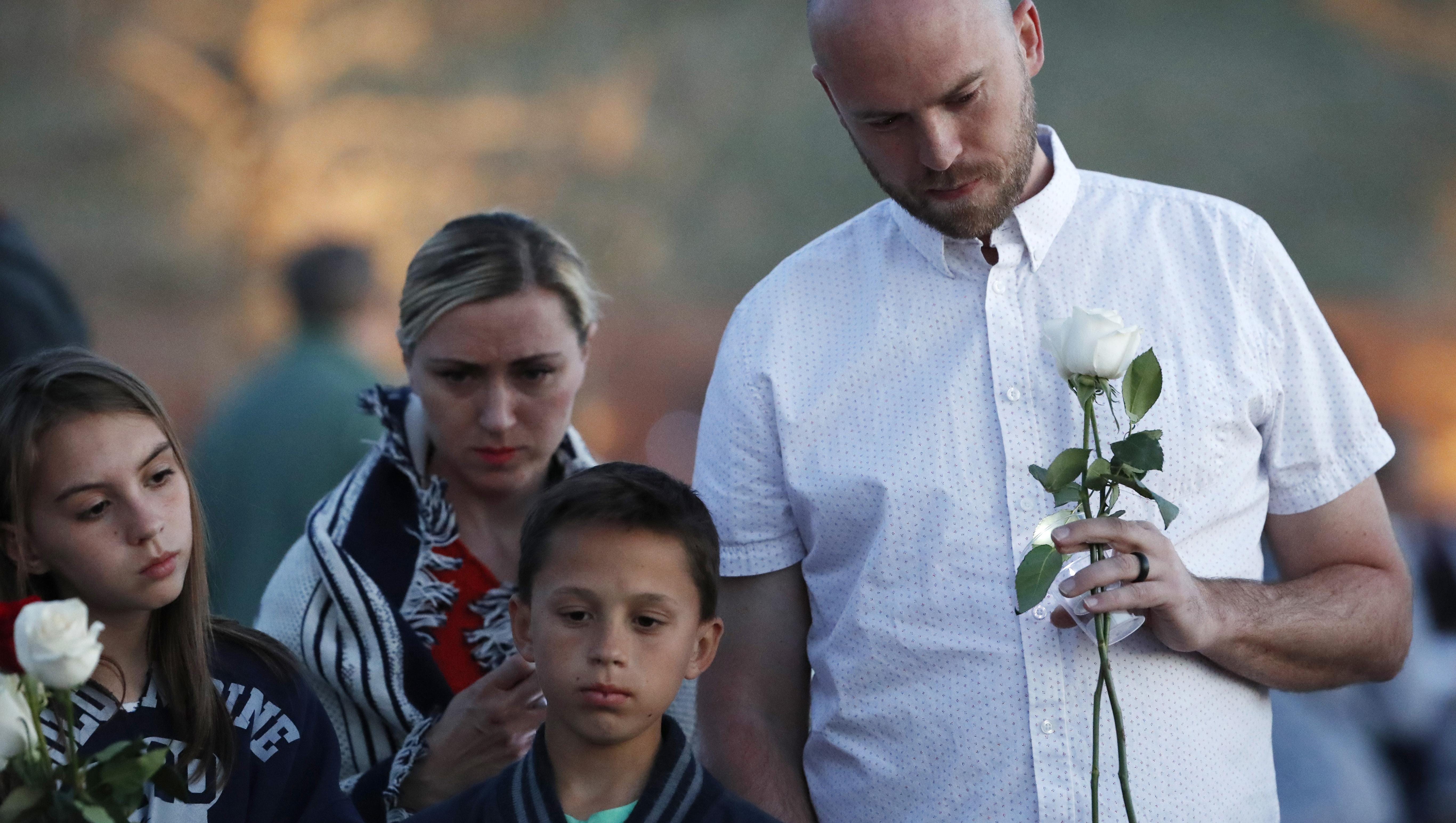 Will Beck, right, who escaped during the shooting attack nearly 20 years ago, joins his family during a vigil at the memorial for the victims of the massacre Friday, April 19, 2019, in Littleton, Colo.