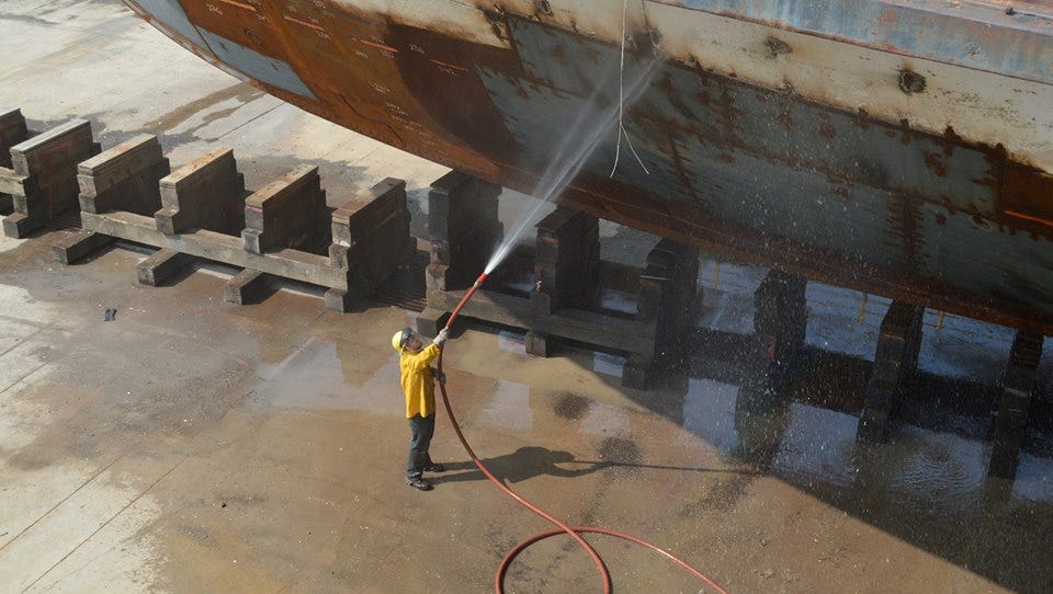 A workman washes the hull of the SS Columbia in 2015.