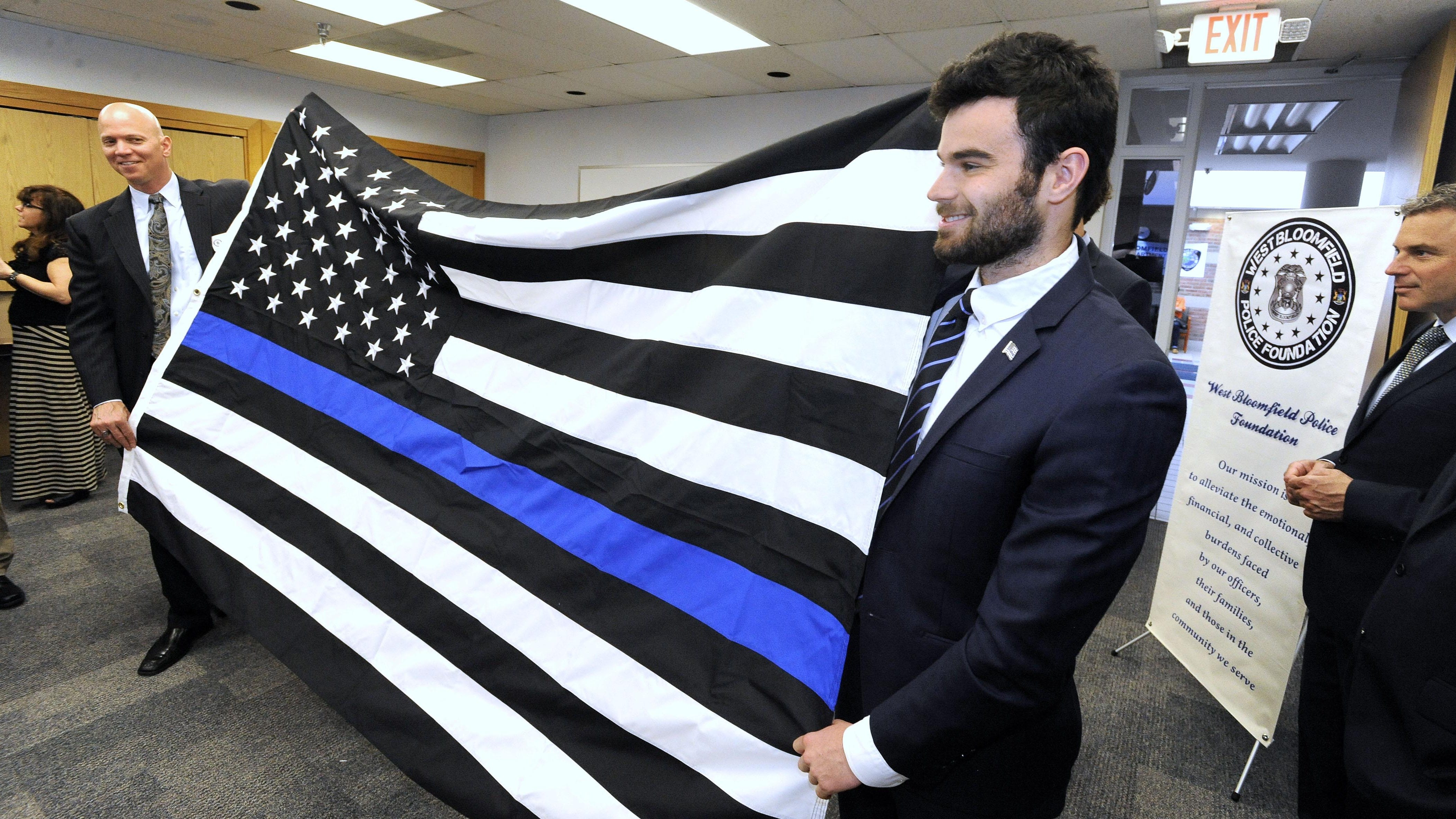 Thin Blue Line president Andrew Jacob, right, presents West Bloomfield Deputy Chief Curt Lawson with a Thin Blue Line flag. The motif could mean a number of things, including a representation of fallen officers.