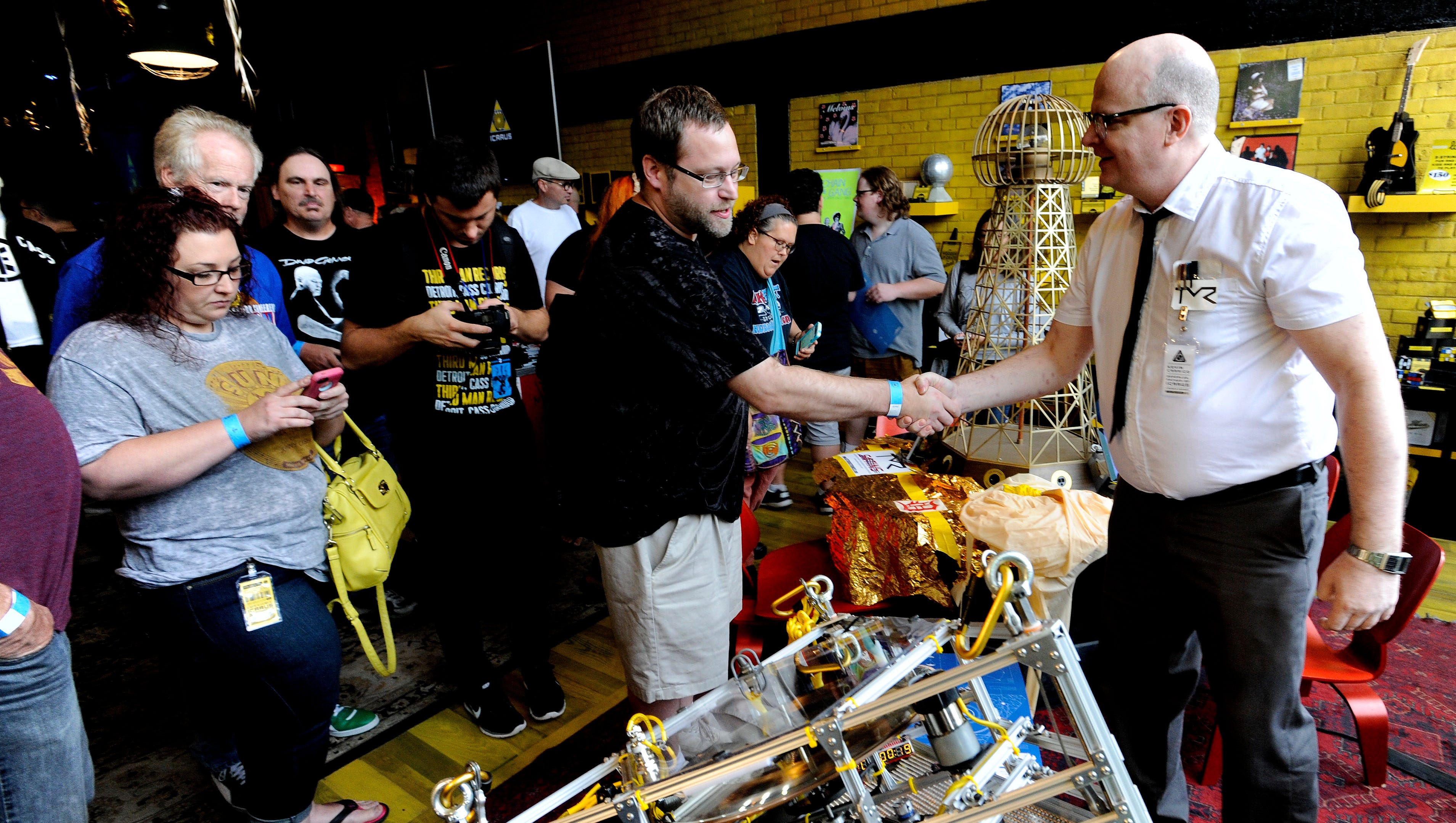 Darrell Wright, left, 40, of Fenton, shakes hands with Kevin Carrico, of Royal Oak, the special projects engineer who built the Icarus Craft. 
Fans attended a watch party at Third Man Records in Detroit for the first phonograph record to be played in space on Saturday, July 30, 2016.
