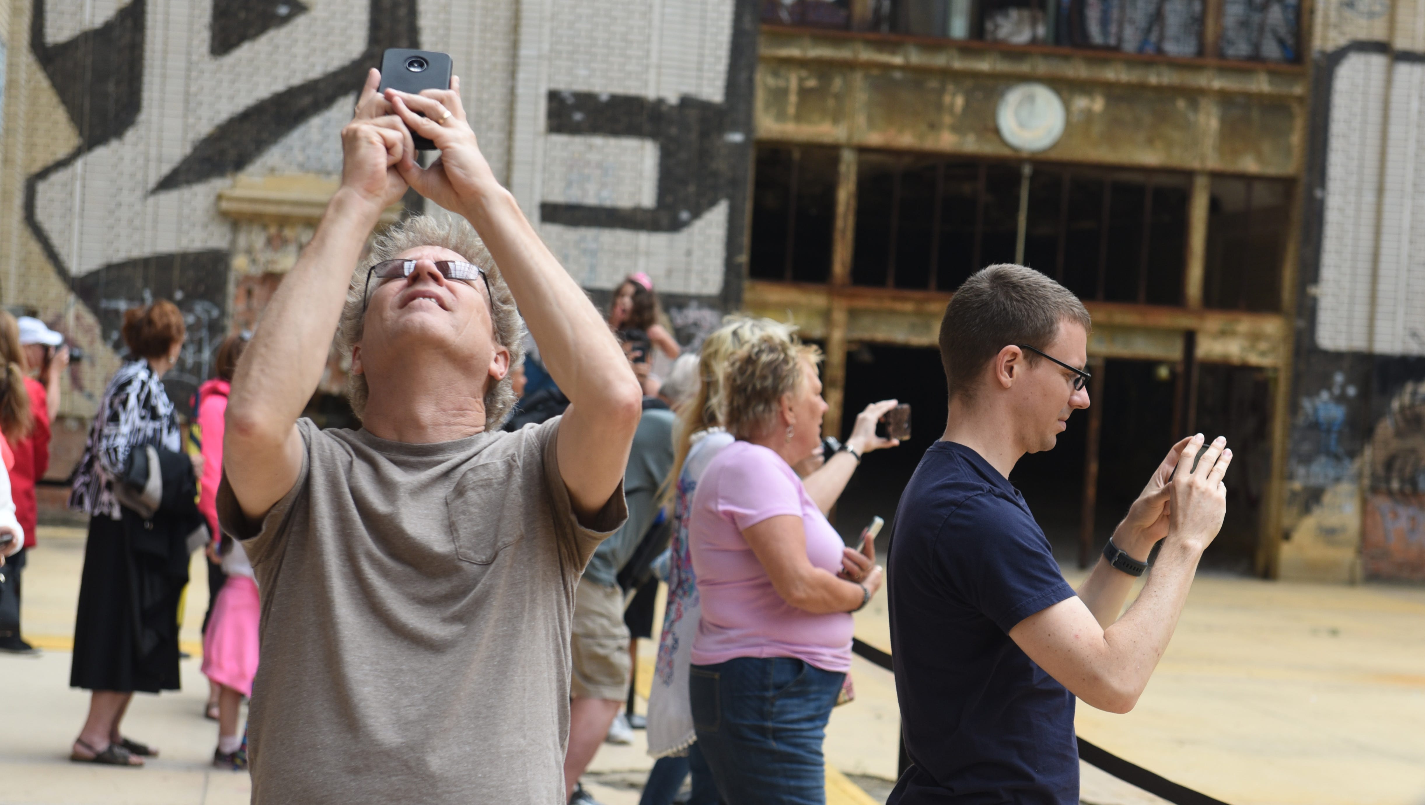 People use their phones to take photographs in the concourse during a public tour of the Michigan Central Train Depot .