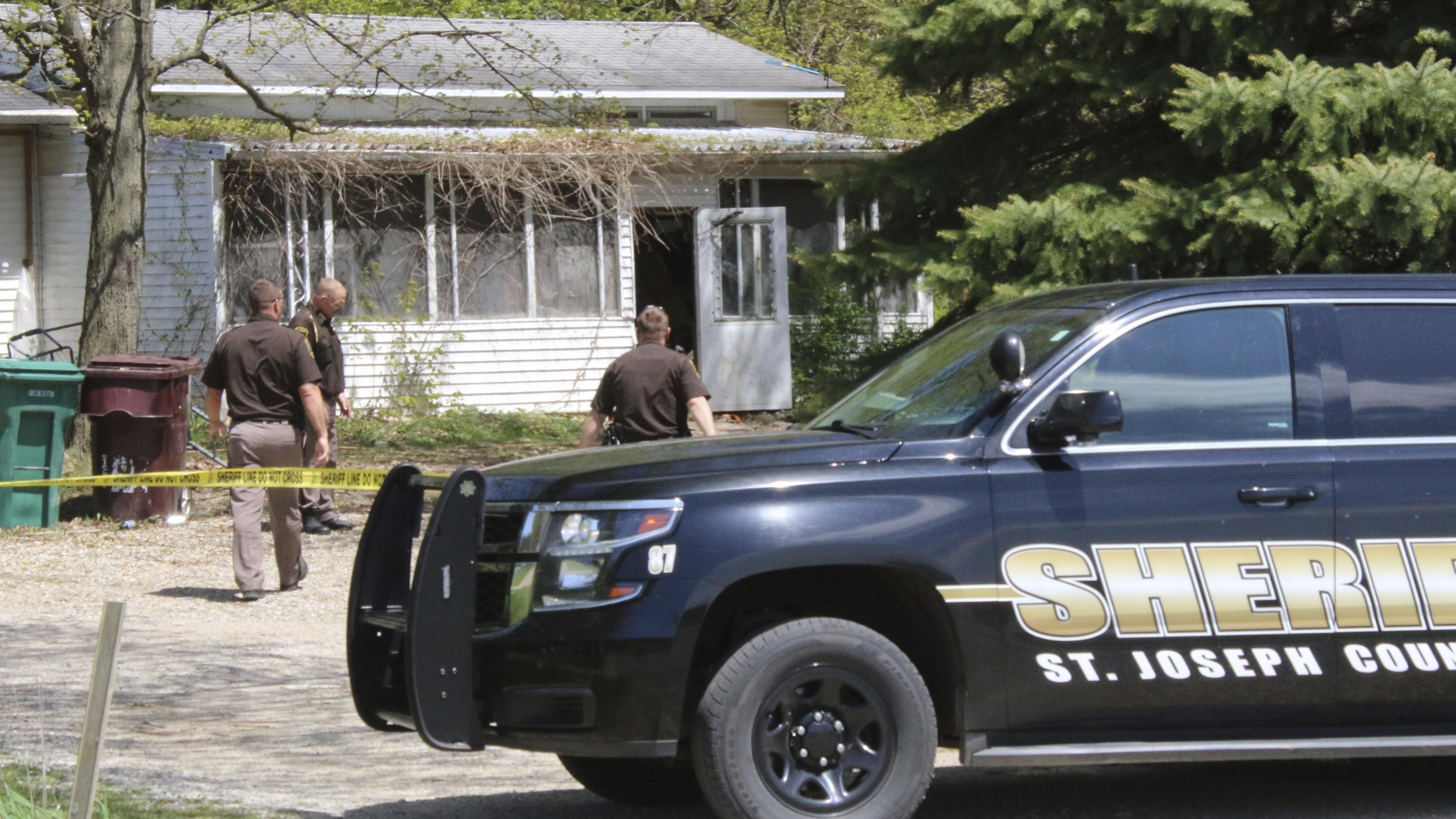 In this Monday, May 6, 2019 photo, St. Joseph County Sheriff deputies stand outside the site where a woman was fatally shot in Fawn River Township, Mich. Authorities say a 9-year-old is suspected in the shooting of a woman in her southern Michigan home.