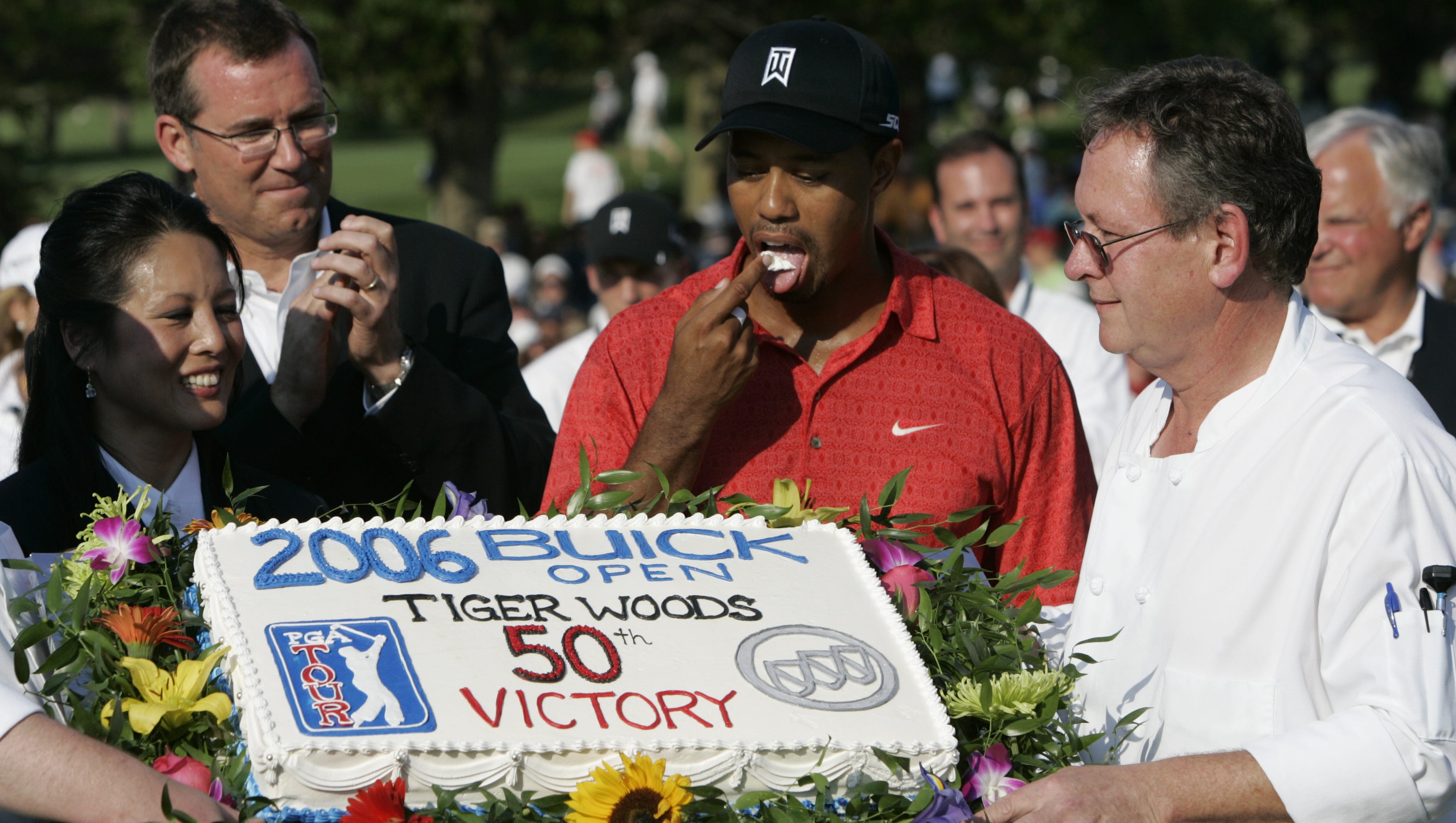 Tiger Woods samples his cake in front of the crowd at the 2006 Buick Open following his 50th victory on the PGA Tour.
