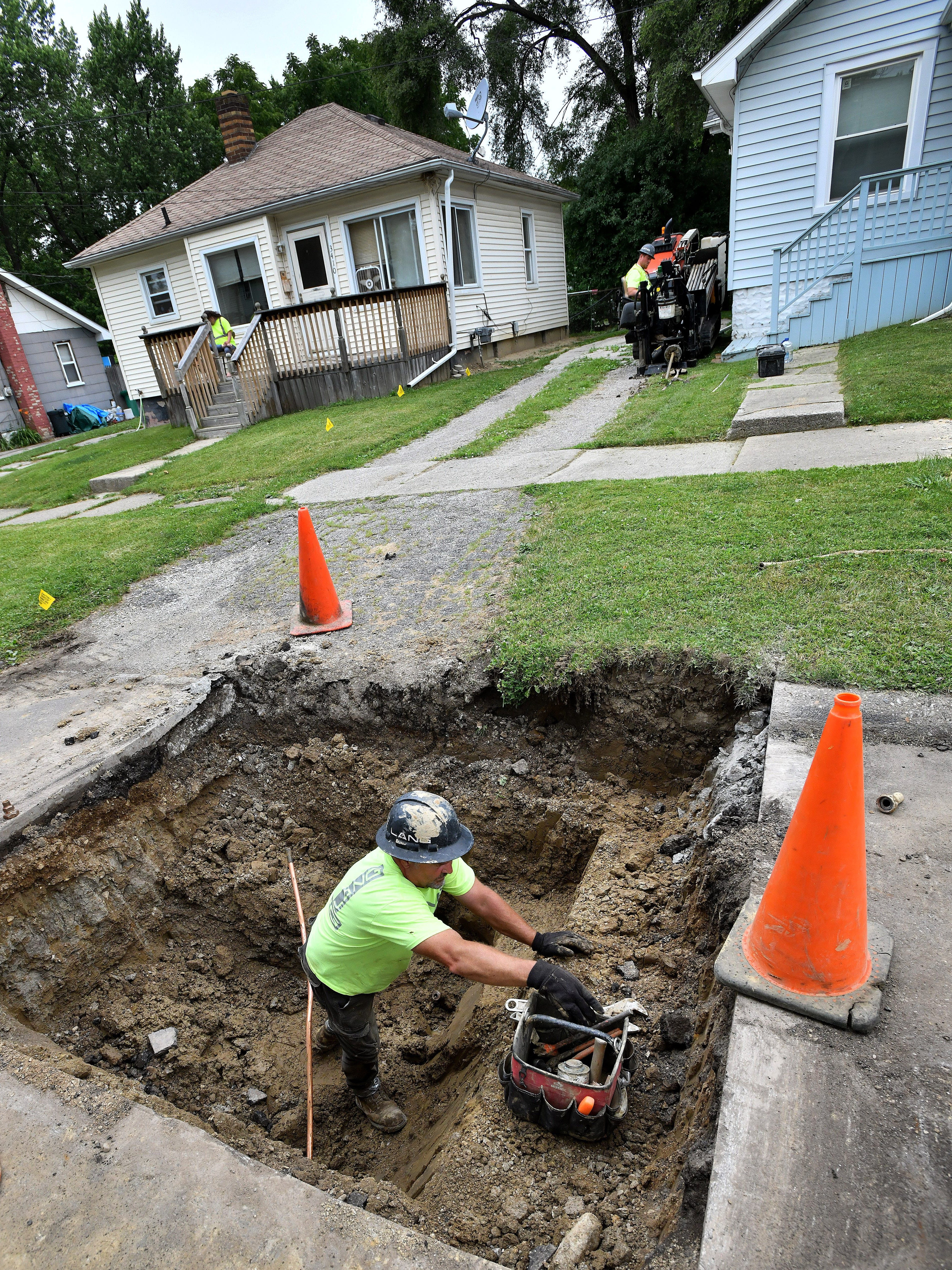 A worker from Lang Construction wrenches fittings in place for new copper pipe as they replace water lines on Arlene Street in Flint.