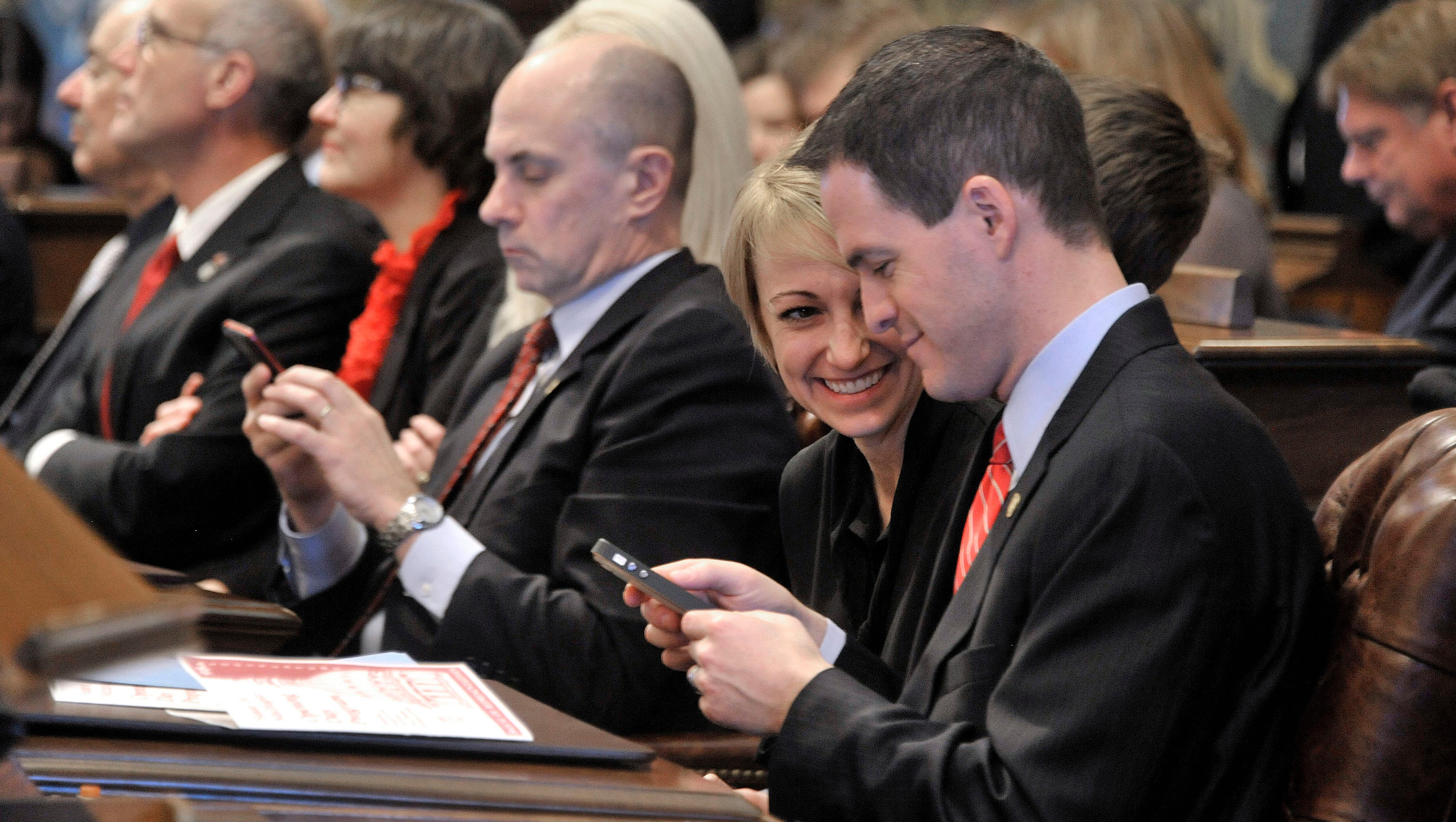 The new Speaker of the House, Kevin Cotter, R-Mount Pleasant, shares a chuckle with his wife, Jennifer, after all the seats were selected. Rep. Gary Glenn, R-Midland, uses his phone in the background.