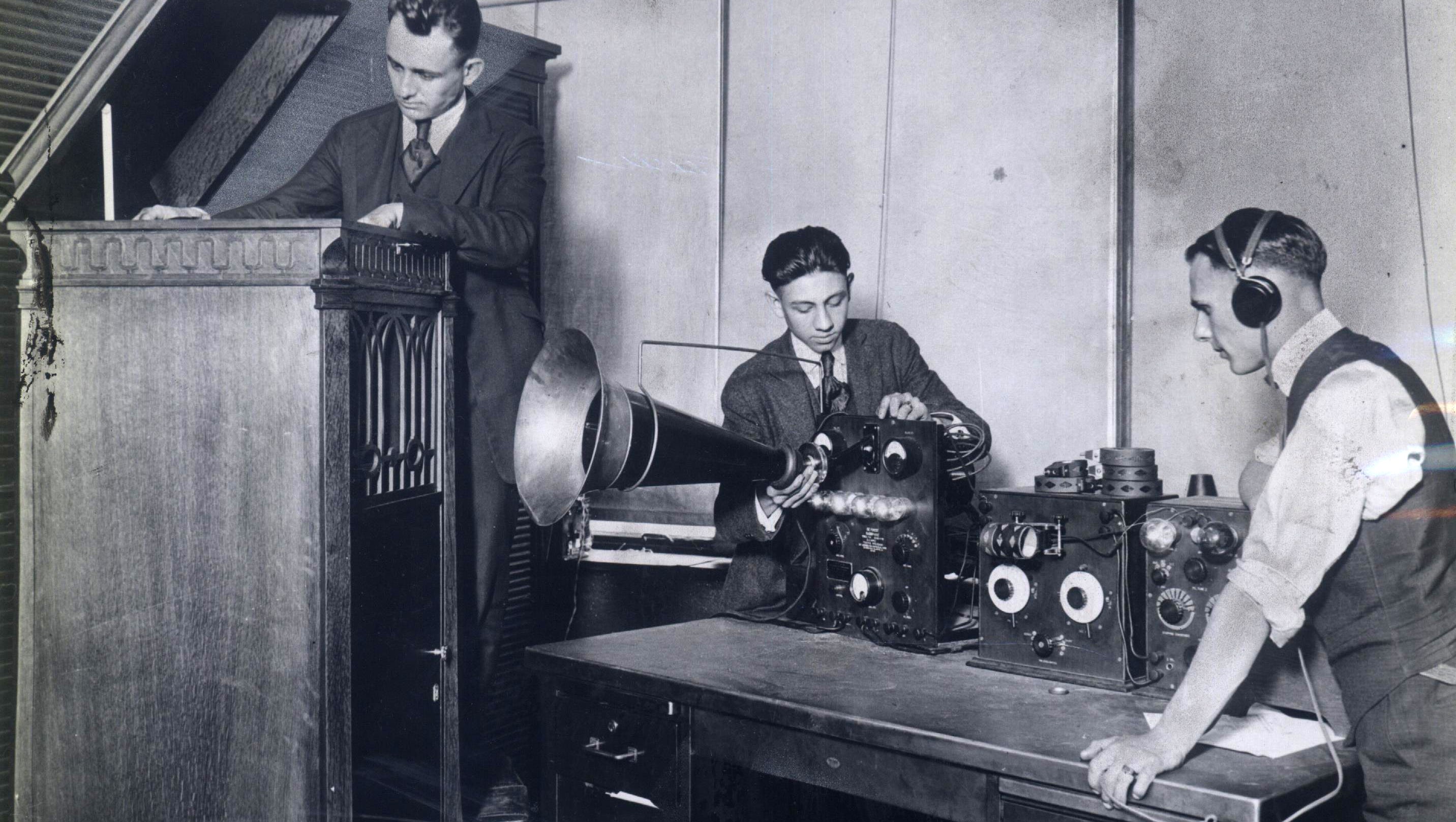 This photo made a short time after Aug. 20, 1920 approximates the scene that night in The Detroit News' makeshift studio, when station 8MK went on the air for the first time. From left are Howard Trumbo, a record shop manager who took part in the event; Detroit News office boy Elton Plant; and radio engineer Frank Edwards.  Plant was drafted as the announcer because he had a good speaking and singing voice.