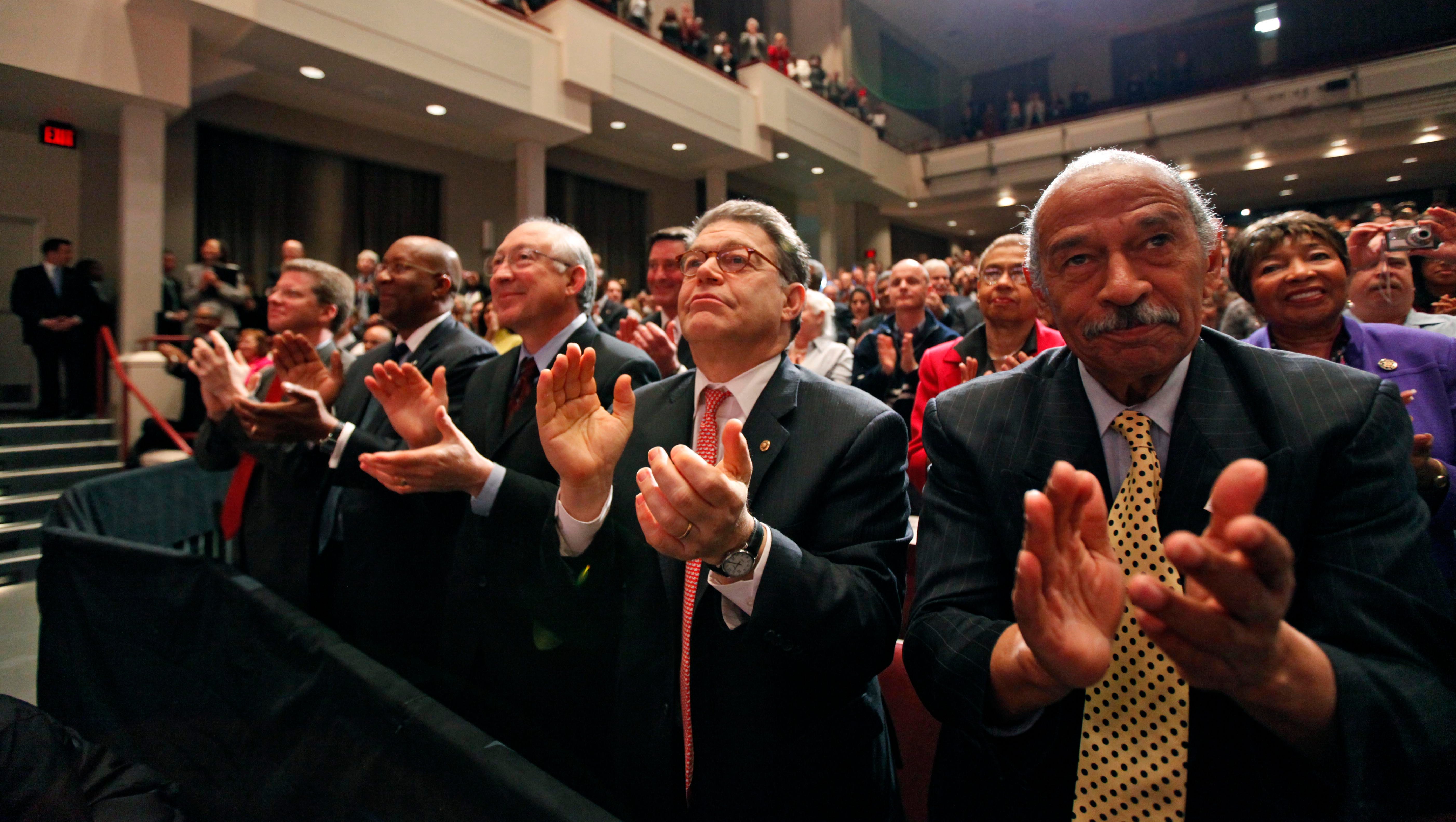 From right, Conyers, Sen. Al Franken, D-Minn., and Secretary of the Interior Ken Salazar applaud as President Barack Obama speaks before signing the landmark health care act in Alexandria, Virginia, March 30, 2010.