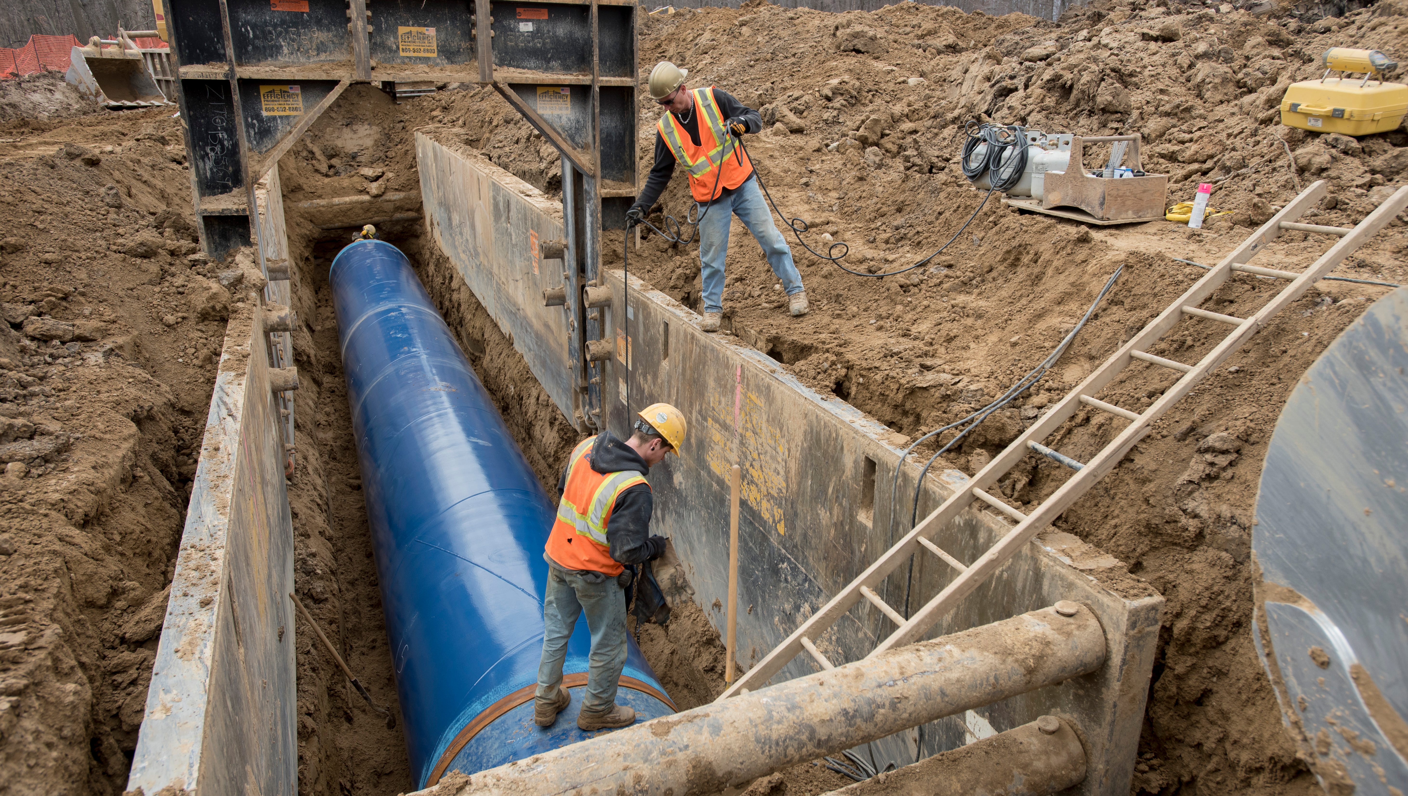 Laborers work on inserting a 50-foot section of the pipeline.