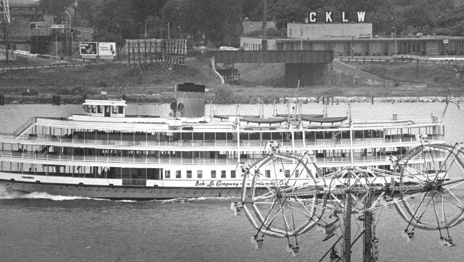 A Boblo boat passes between CKLW, the Canadian pop rock AM powerhouse station of the 1960s, and a double ferris wheel on the island.