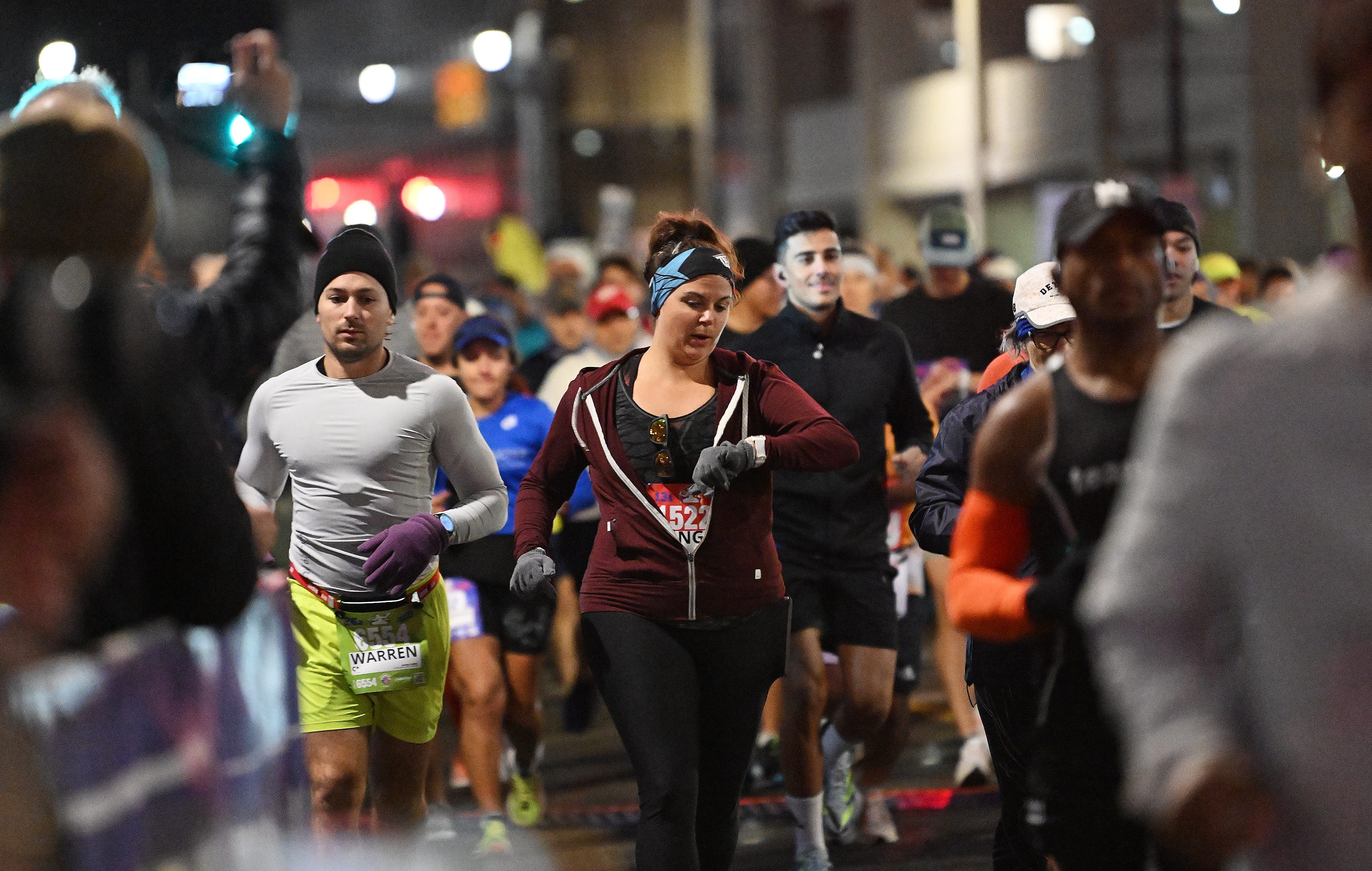 Some runners in the second wave check their times at the start of the Detroit Free Press Marathon on Fort Street in Detroit on Oct. 15, 2023.
