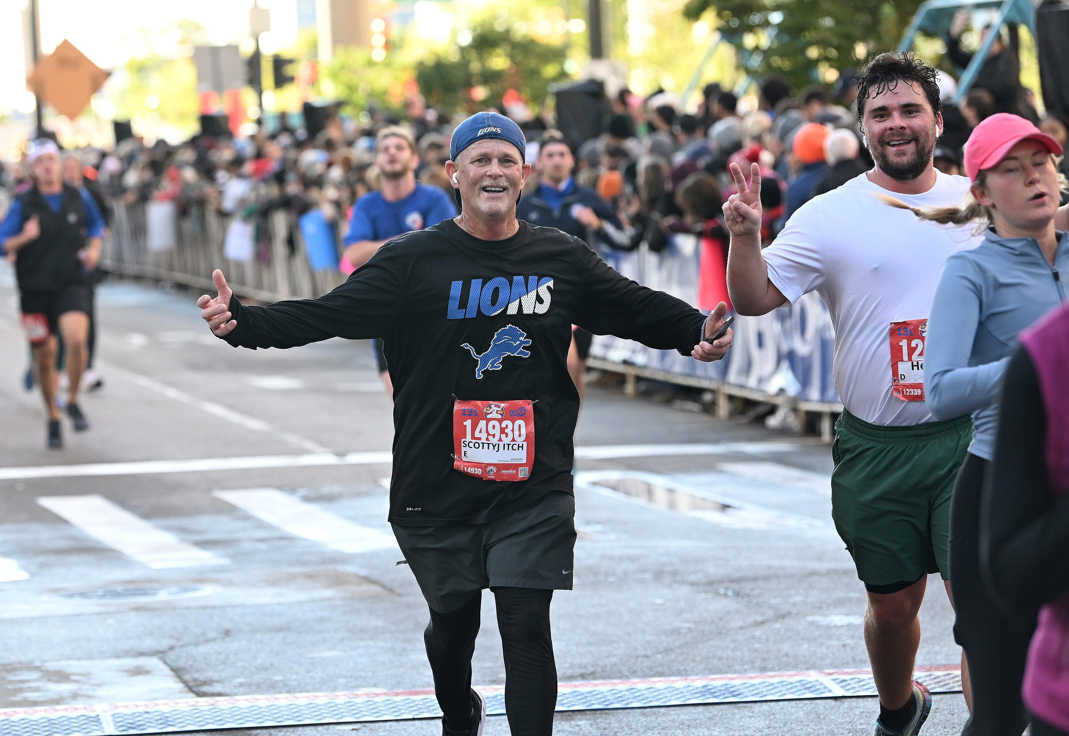 From left, Scott Johnson, 58, of Monroe and Henry Mikesell, 27, of Clawson react after finishing the half marathon at the Detroit Free Press Marathon in Detroit on Oct. 15, 2023.