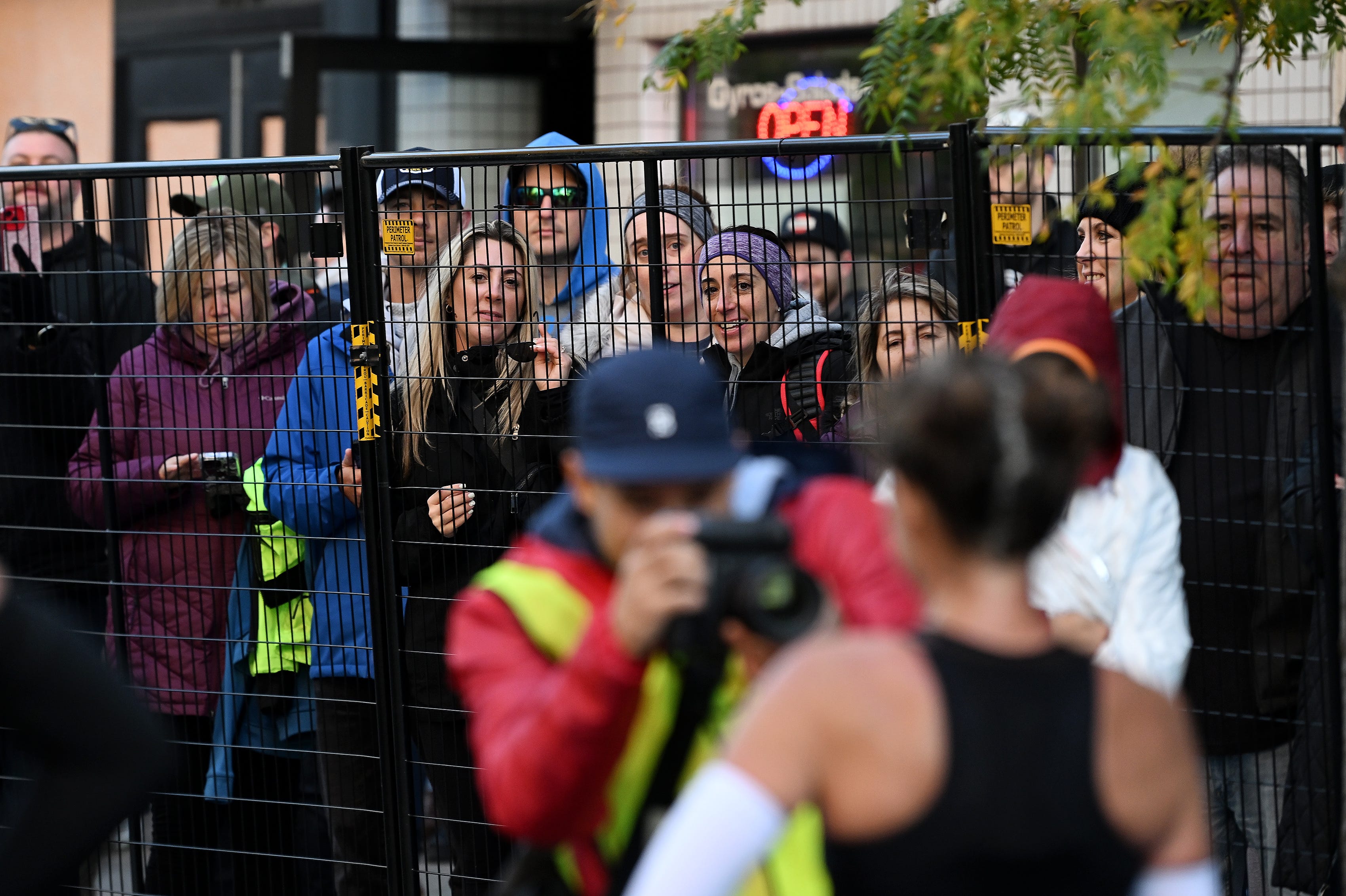 People watch as the women’s marathon winner, Kate Landau, 47, of Tacoma is photographed at the Detroit Free Press Marathon.