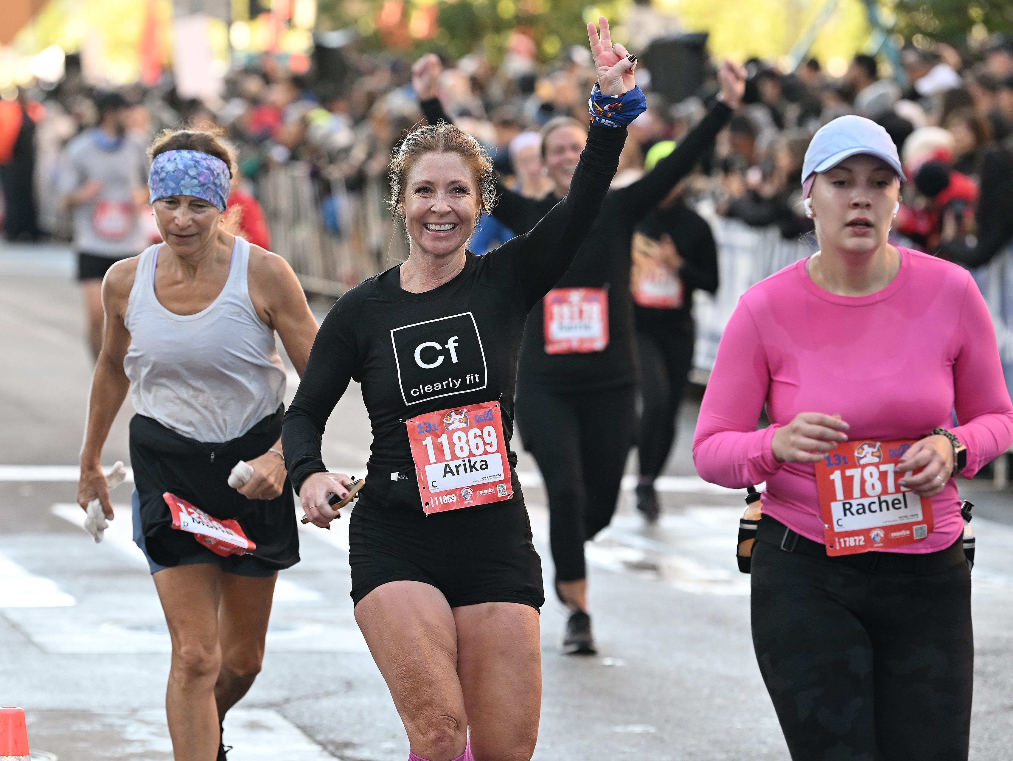 Arika Hundt-Cole, 41, of Williamston, center, reacts as she finishes the half marathon.